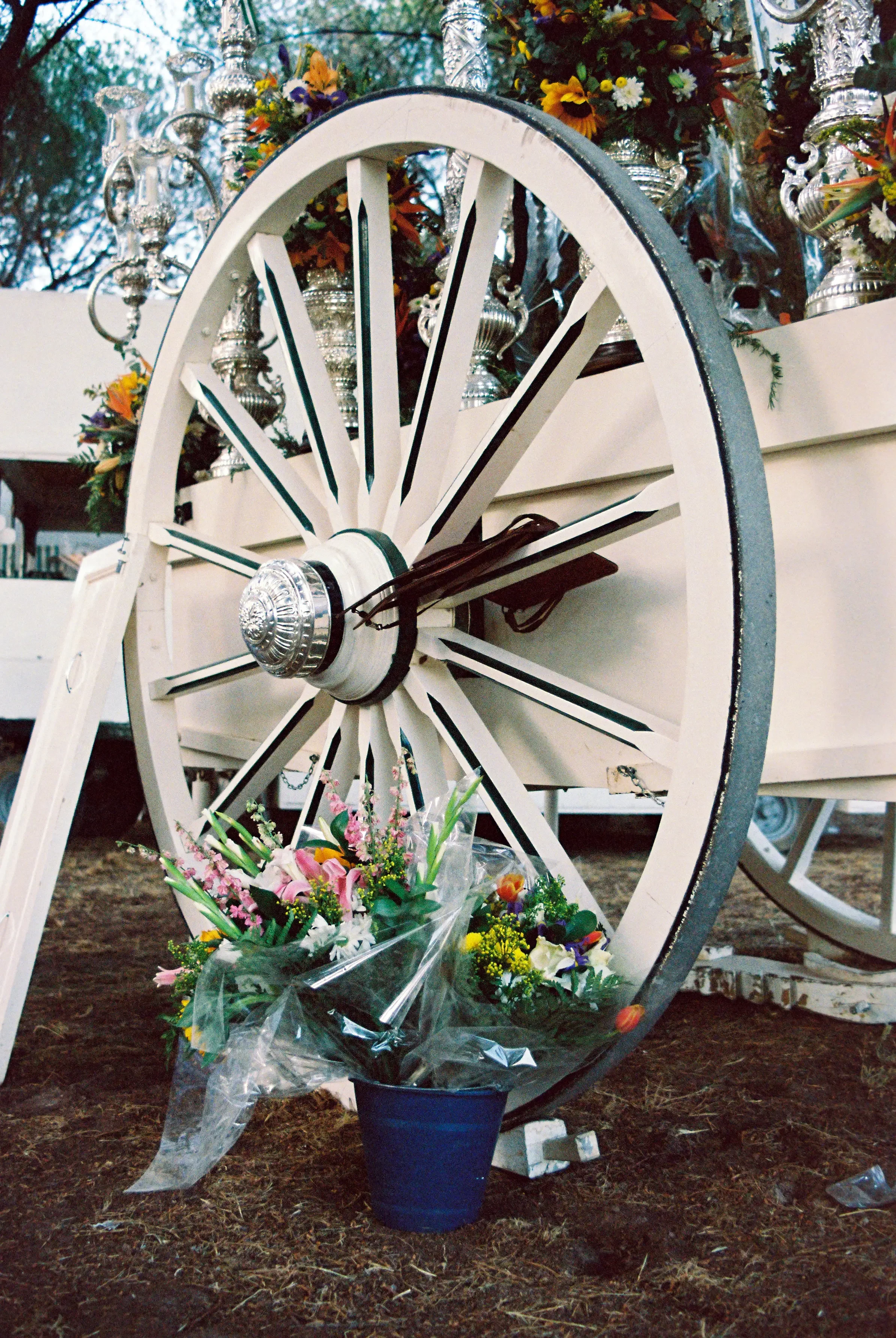 Carreta decorada con flores y objetos plateados, en un evento al aire libre.
