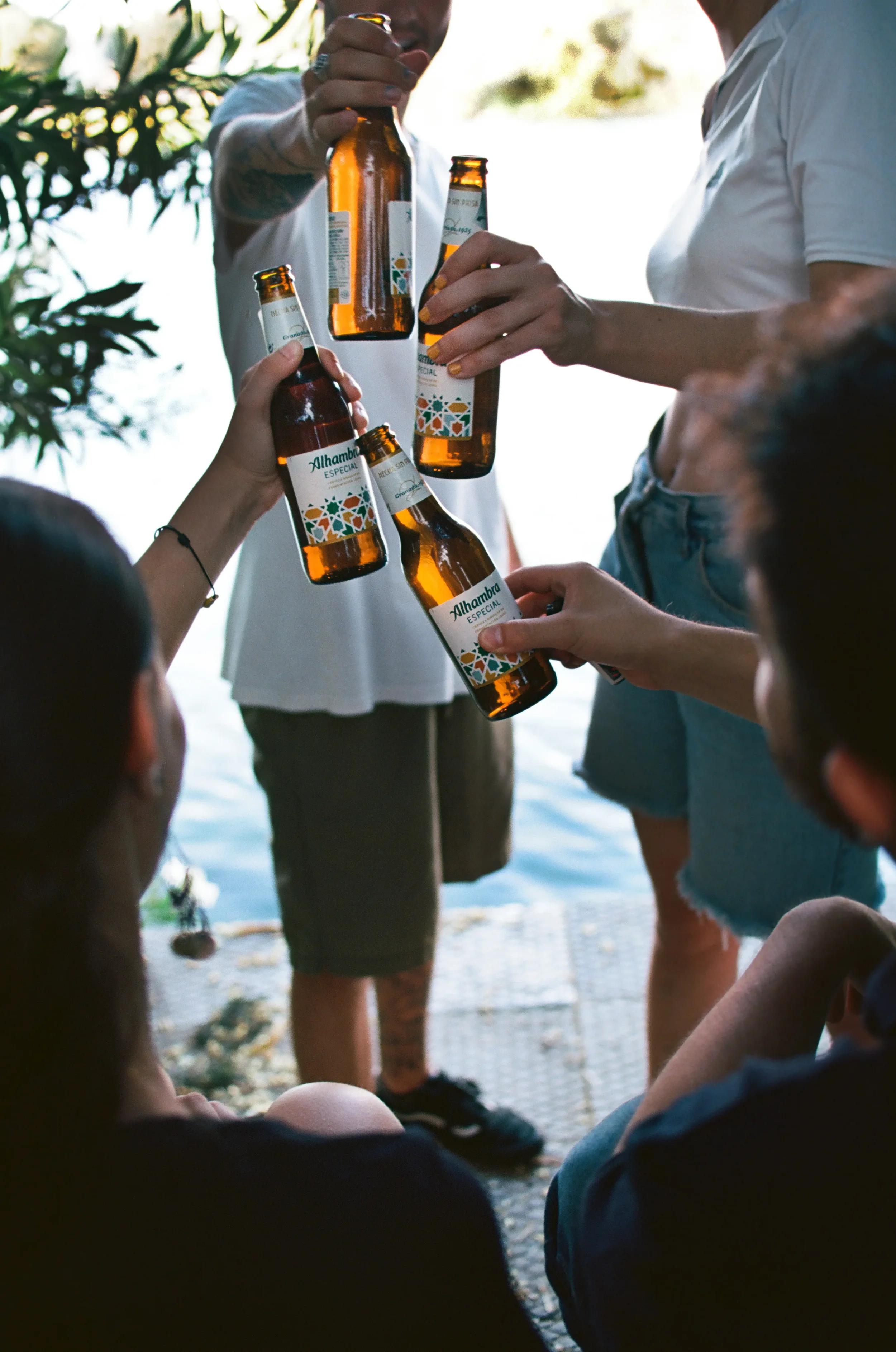 Varias personas en un momento de celebración, brindando con botellas de cerveza en un entorno natural junto a un río.