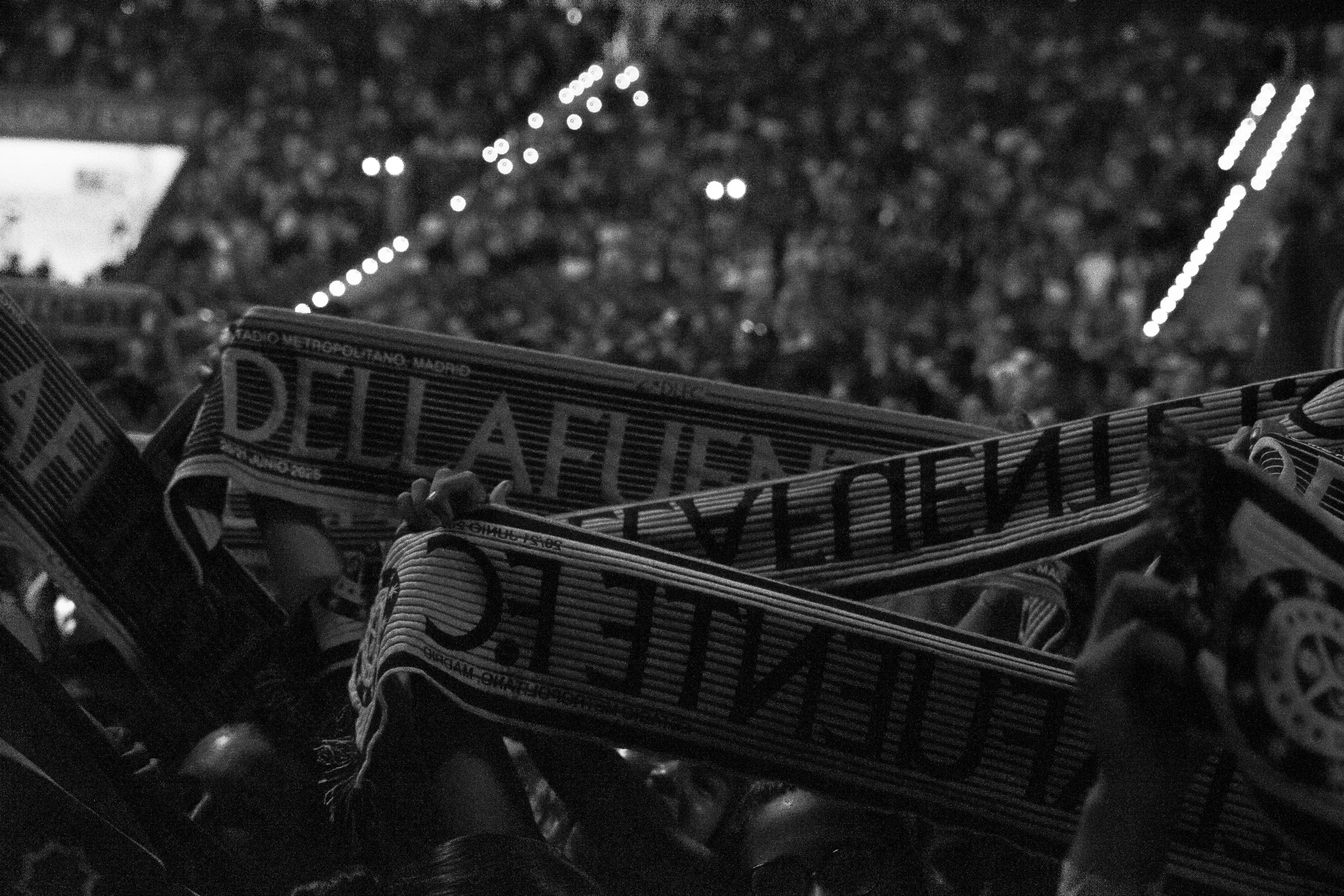 Bandeja con objetos apilados y letras que dicen 'Real Madrid' en primer plano, vista desde arriba con fondo de luces diffuse en la noche.