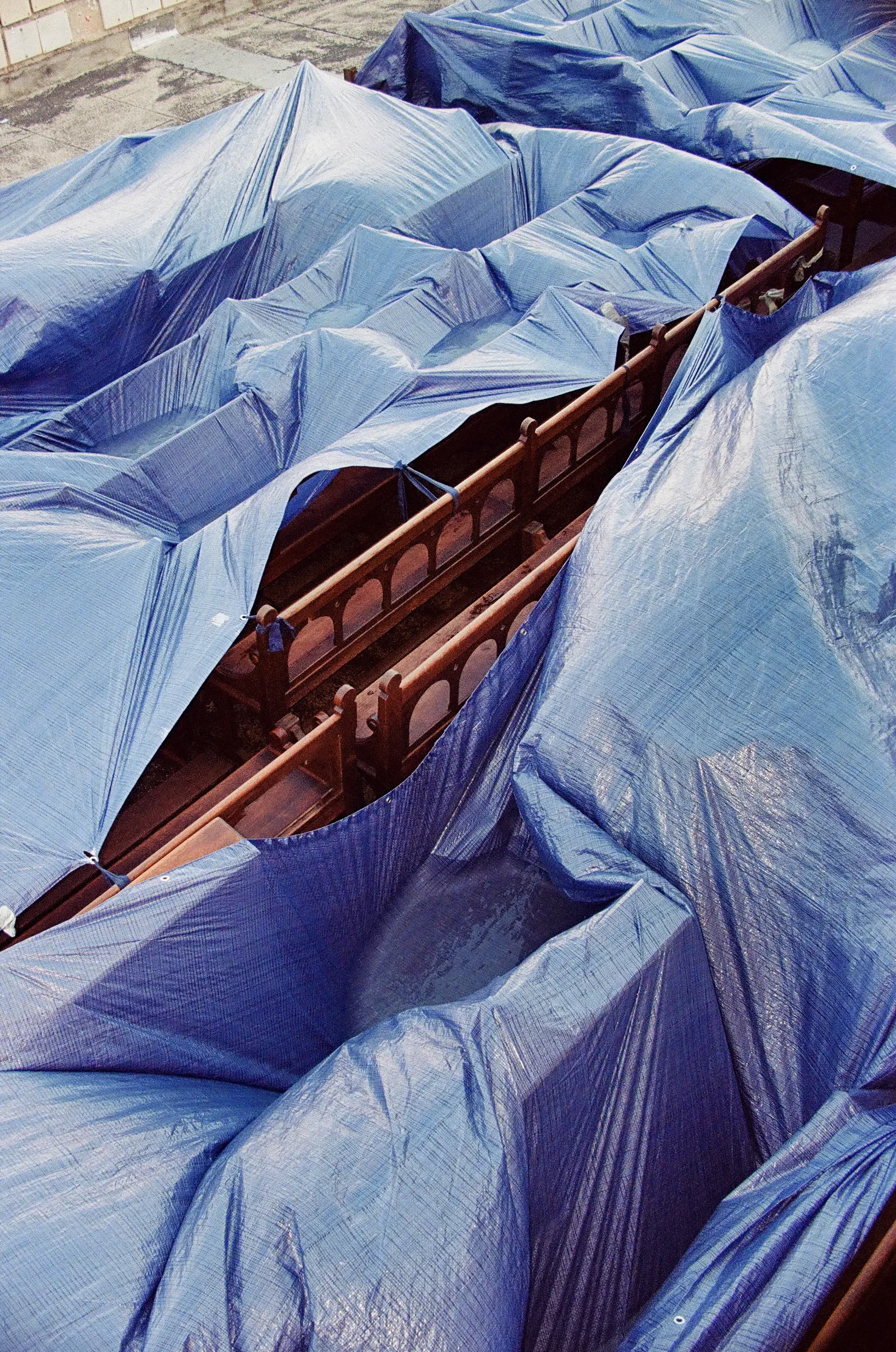 Cubiertas azules en un espacio exterior con un banco de madera debajo de ellas.
