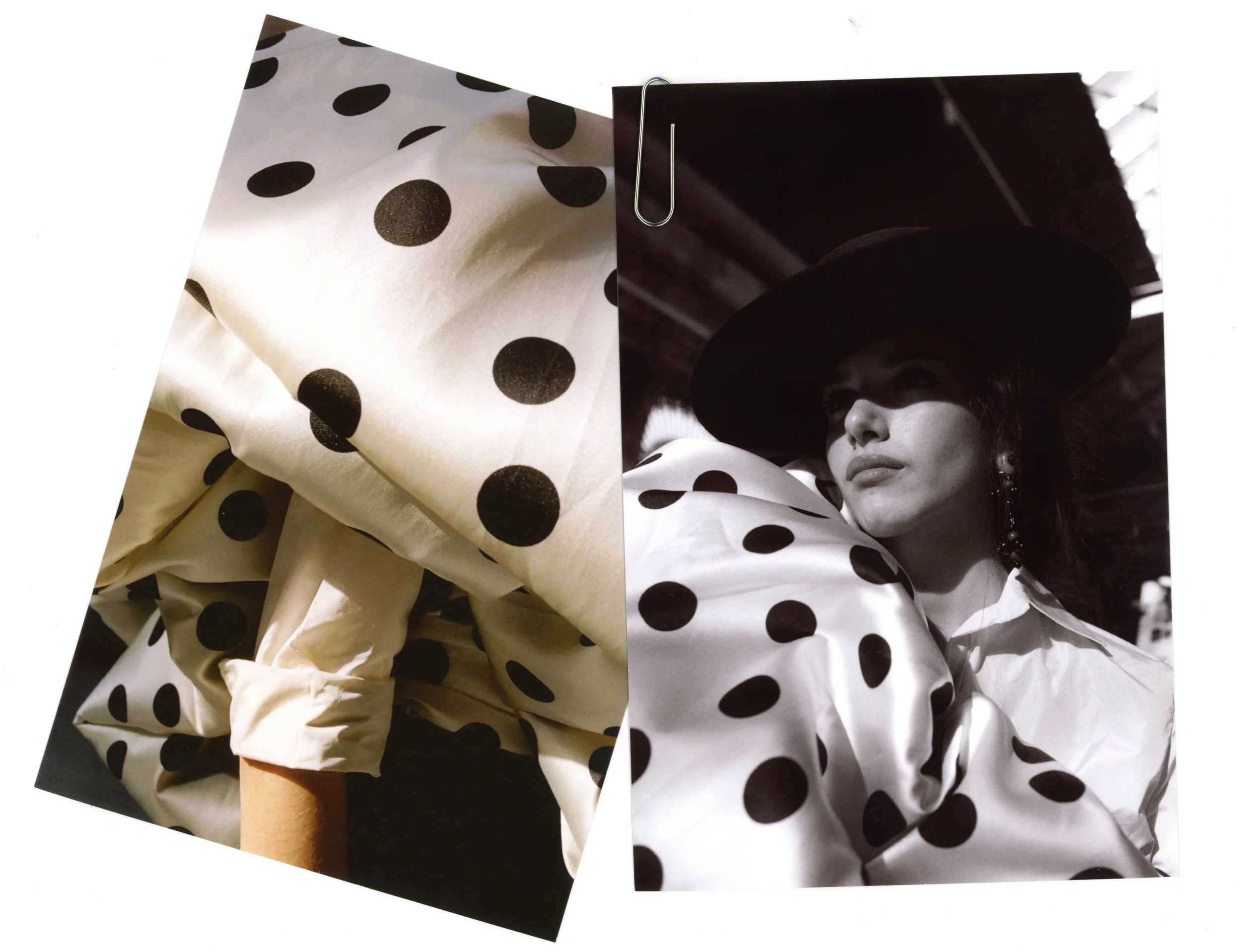 Fotografía en blanco y negro de una mujer usando un sombrero grande, con ojos cerrados o mirando hacia abajo, en un entorno que parece un estudio o escenario, rodeada de telas con diseño de puntos en tonos claros y oscuros, incluida una pieza con pun