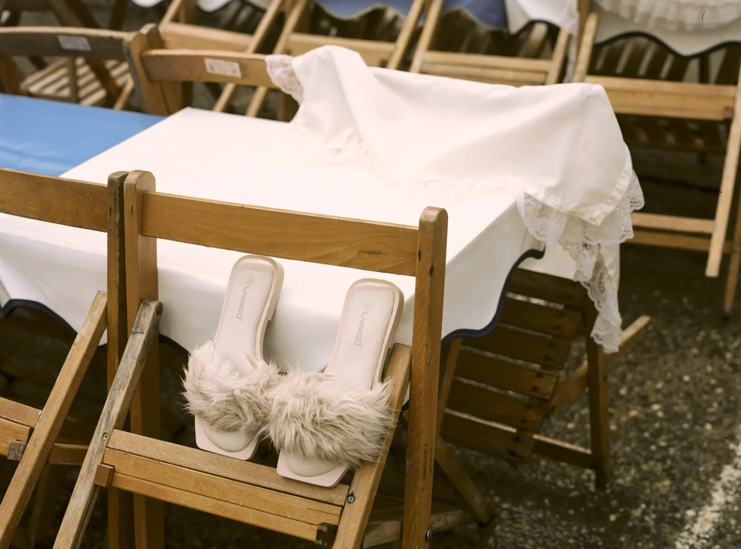 Sillas de madera apiladas con una silla decorada con una manta de peluche y una bolsa blanca en la mesa.
