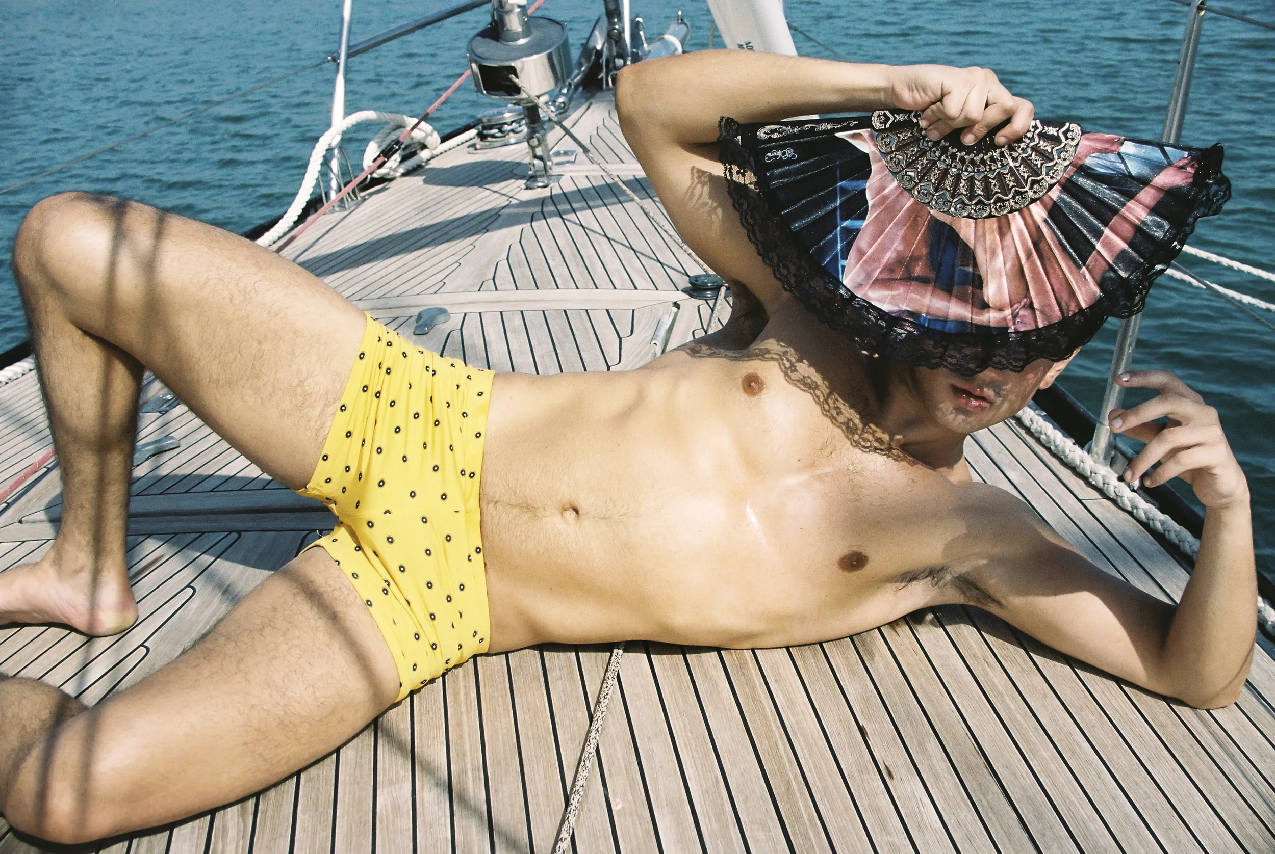 Hombre descansando en un yate con sexo hombre, sombrero y bañador amarillo en un día soleado en el mar.