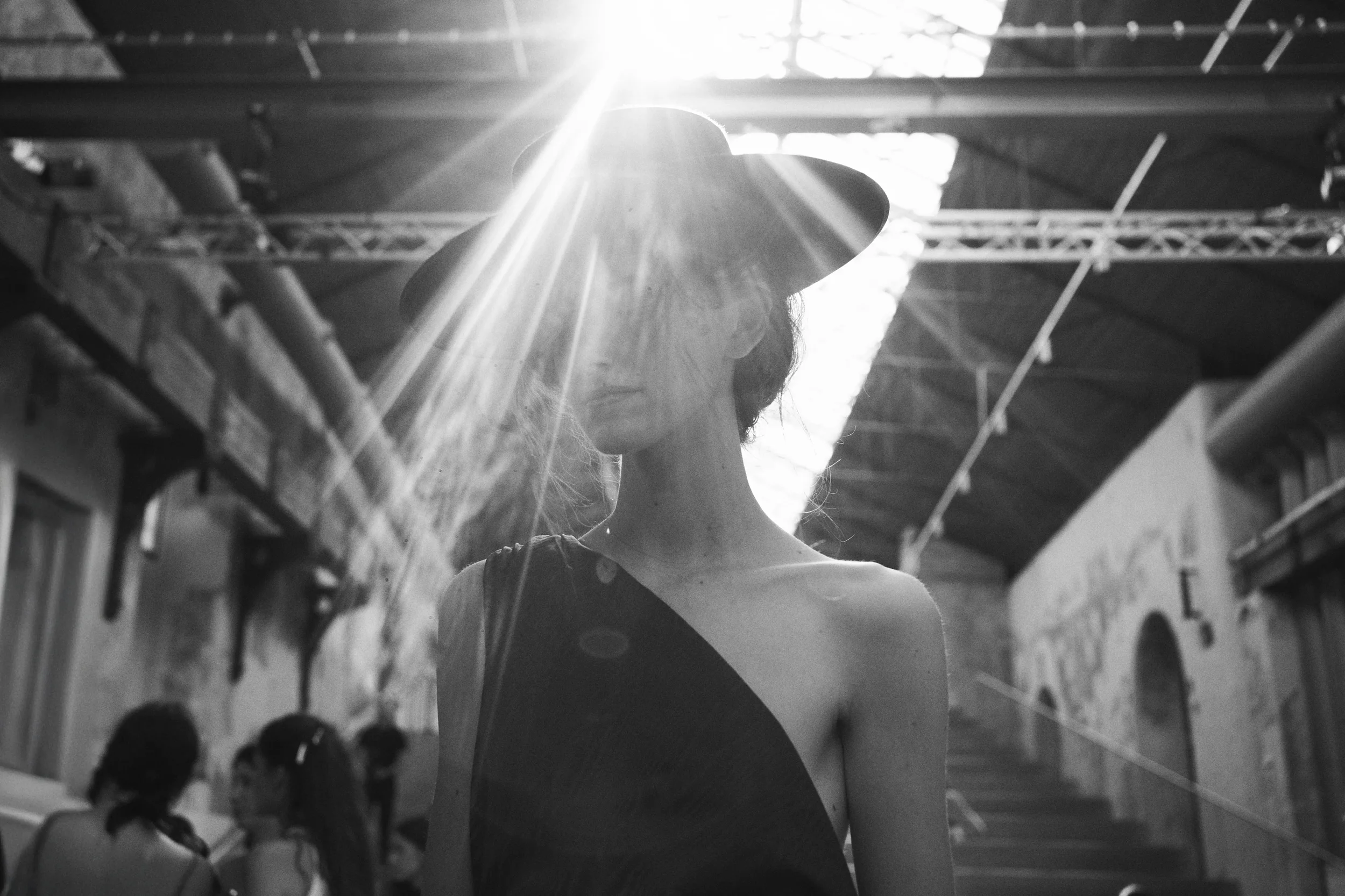 Mujer con sombrero en un espacio industrial iluminado por luz solar