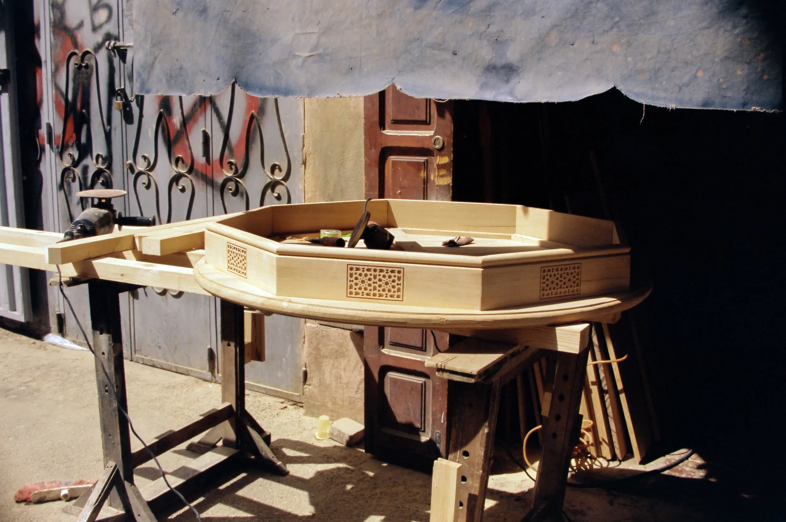 Mesa de trabajo de madera en proceso de construcción con herramientas y materiales alrededor.
