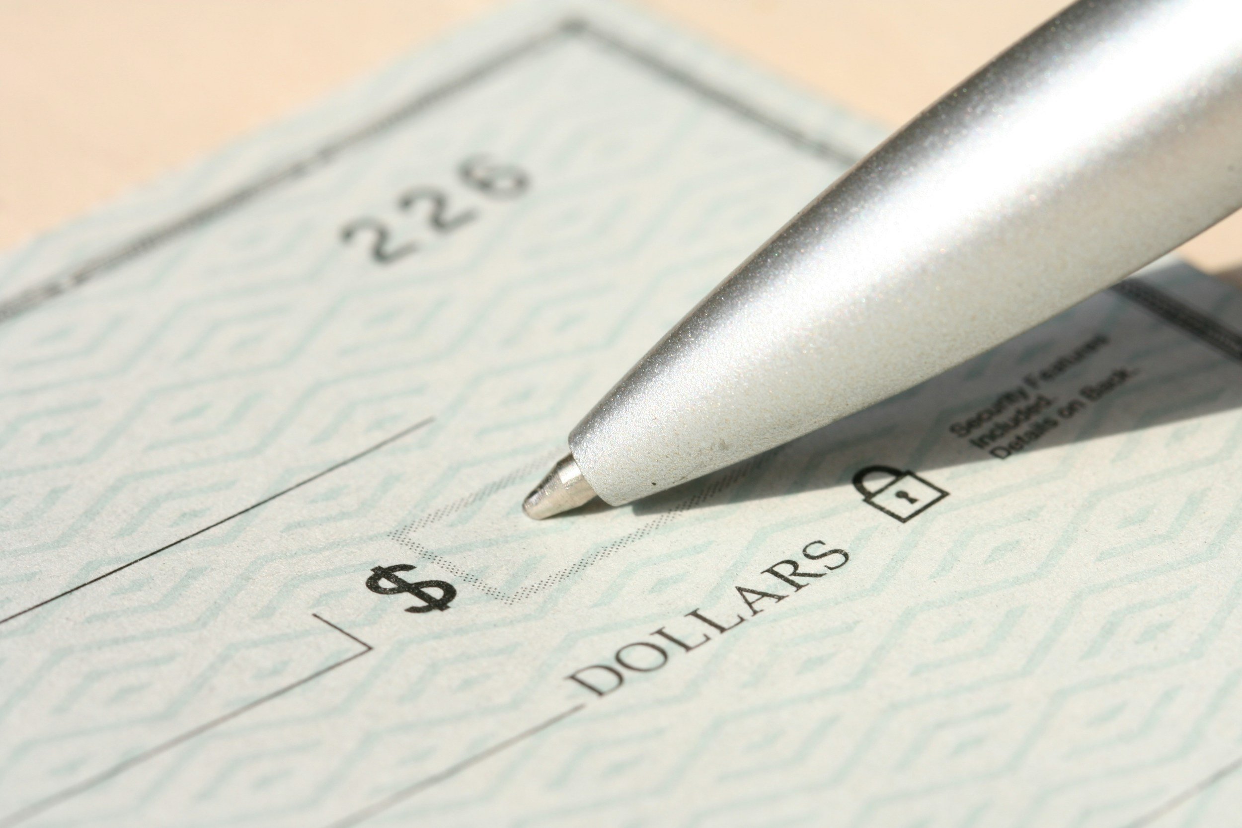 Close-up of a black pen marking a check box on a check written for $22.50.