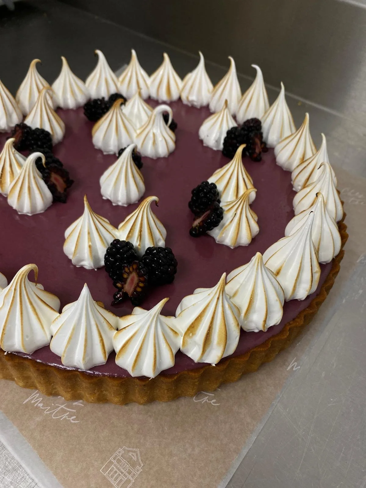 A berry tart topped with meringue peaks and blackberries.
