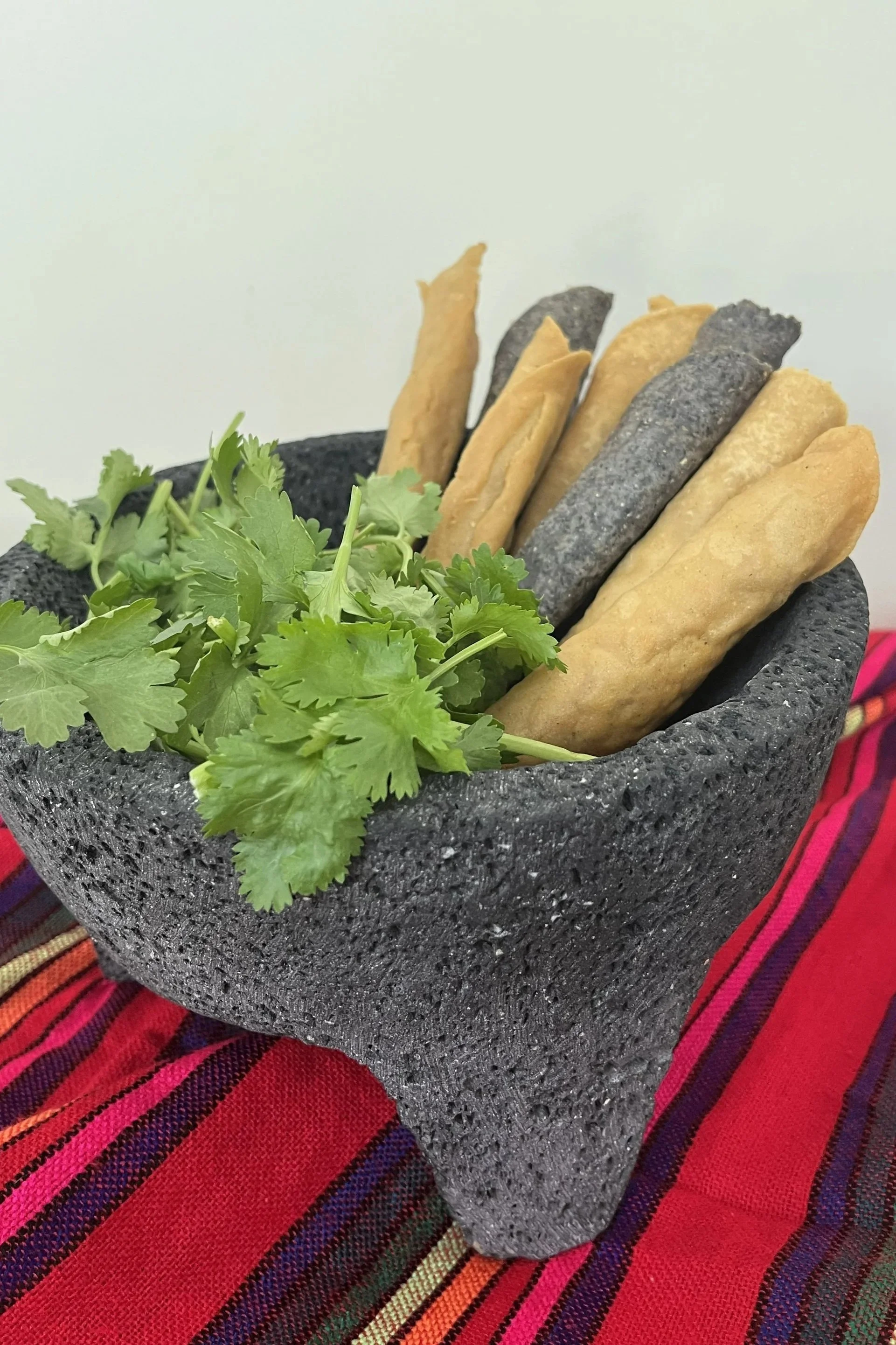 A Mexican Molcajete with fresh cilantro and loaded with Flautas.