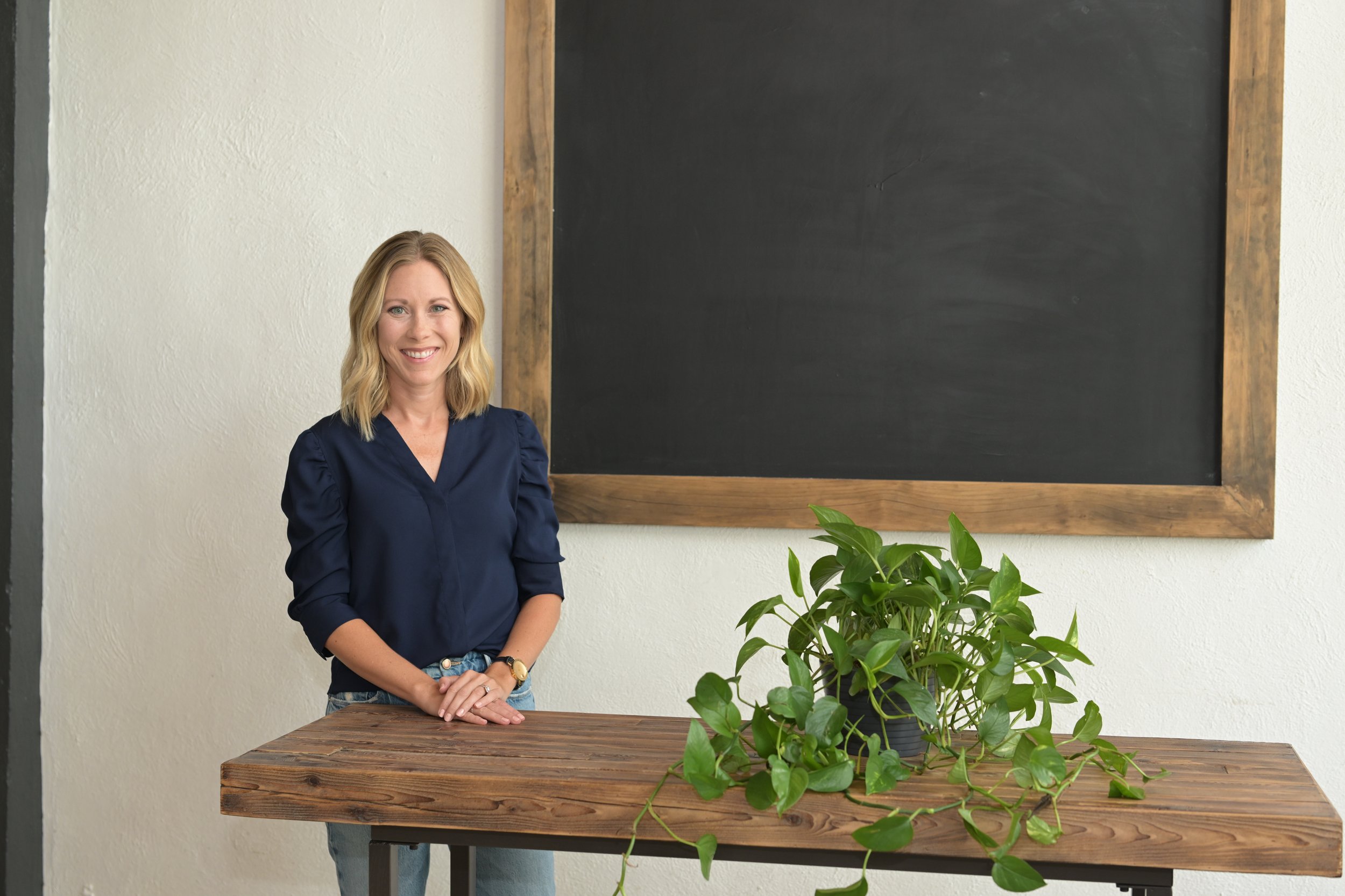 A therapist with a warm smile standing in a relaxed pose.