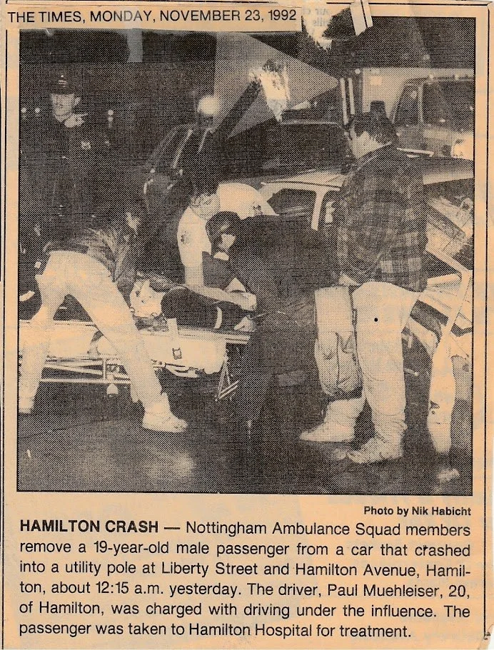 A newspaper photo showing Nottingham Ambulance Squad members assisting a 19-year-old male passenger after a car crash into a utility pole at Liberty Street and Hamilton Avenue, Hamilton, on November 23, 1992. The driver, Paul Muehleiser, was charged with driving under the influence.