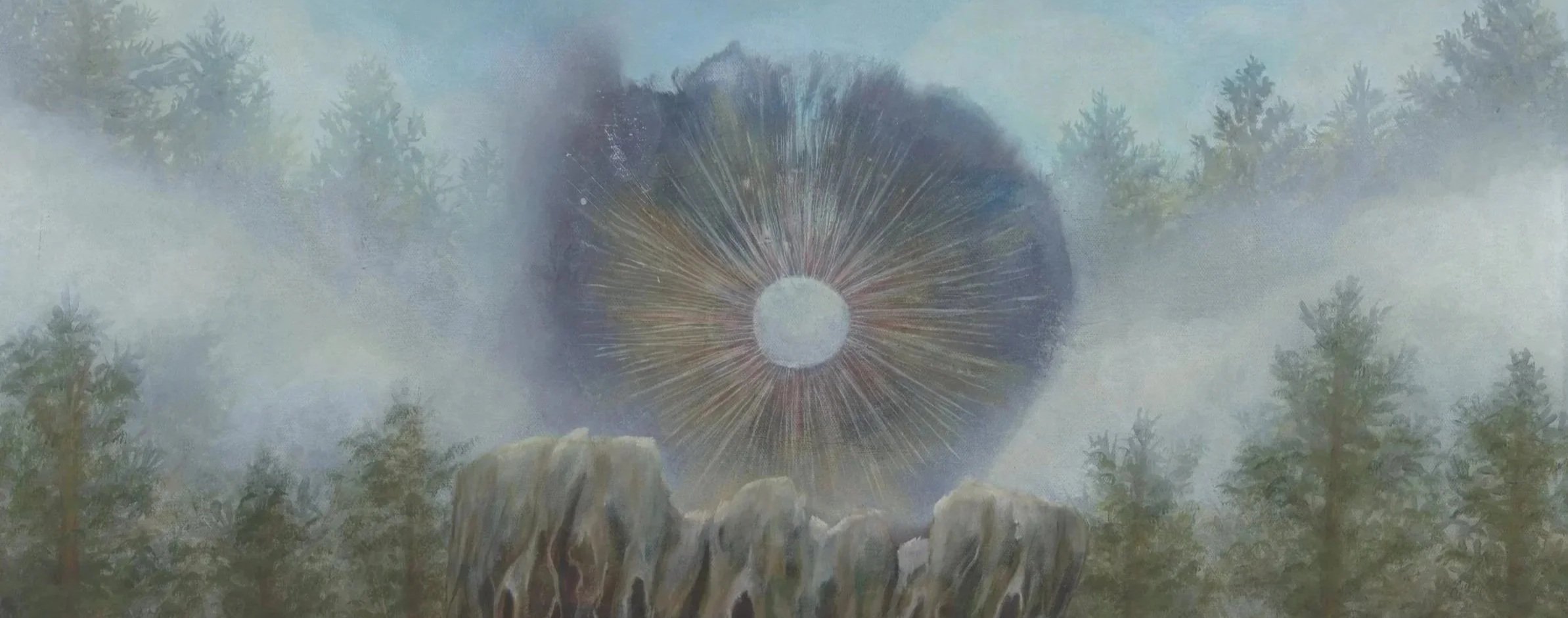 Dreamcatcher hanging outdoors among trees with clouds or fog.