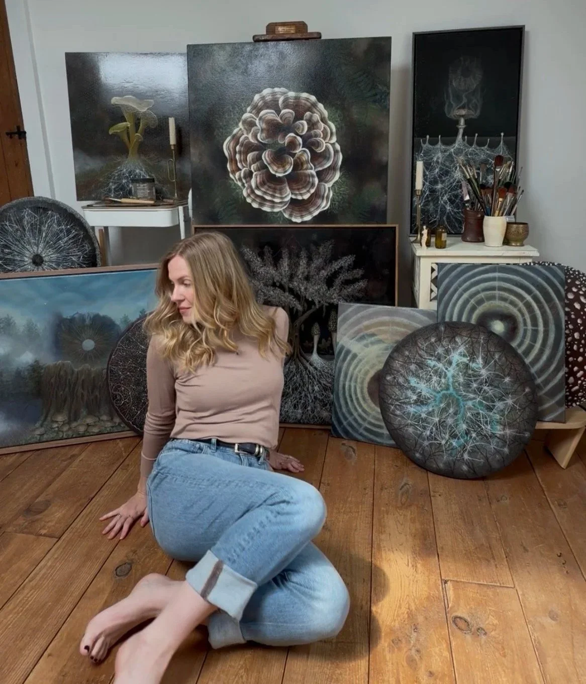 Danielle Masters in her art studio surrounded by oil paintings in her Among Fungi collection