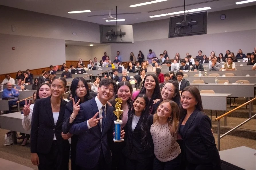 Group of smiling high school students in business attire celebrating with a trophy after winning second place at a high school mock trial tournament. The SoCal Mock Trial League hosts high school mock trial tournaments across Southern California.