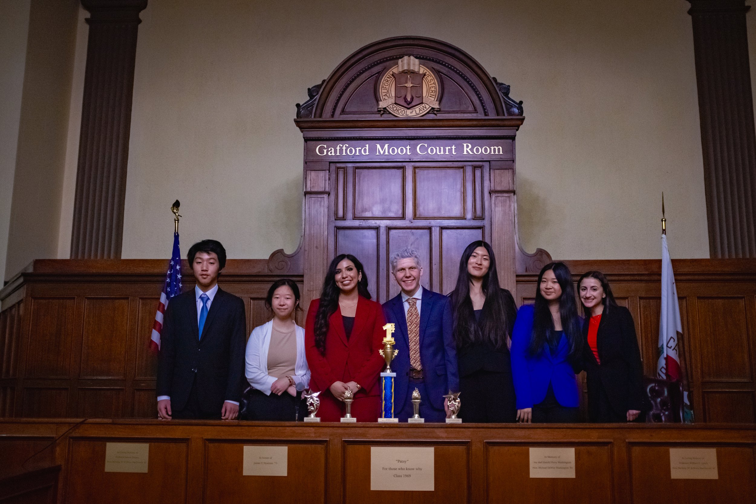 A high school mock trial team poses with their first place trophy in Gafford Moot Court Room at the California Western School of Law, after winning first place in the tournament. The SoCal Mock Trial League hosts high school mock trial tournaments.