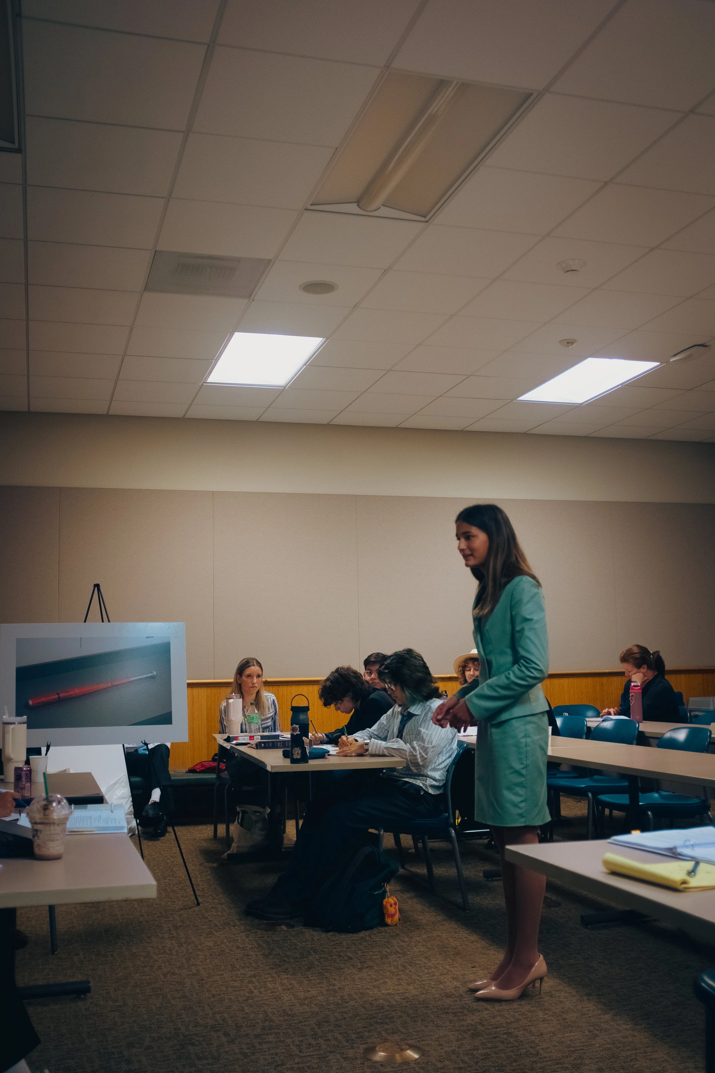 A high school student in a green suit presents her closing statement in a classroom during a high school mock trial tournament. The Southern California Mock Trial League hosts high school mock trial tournaments across Southern California.