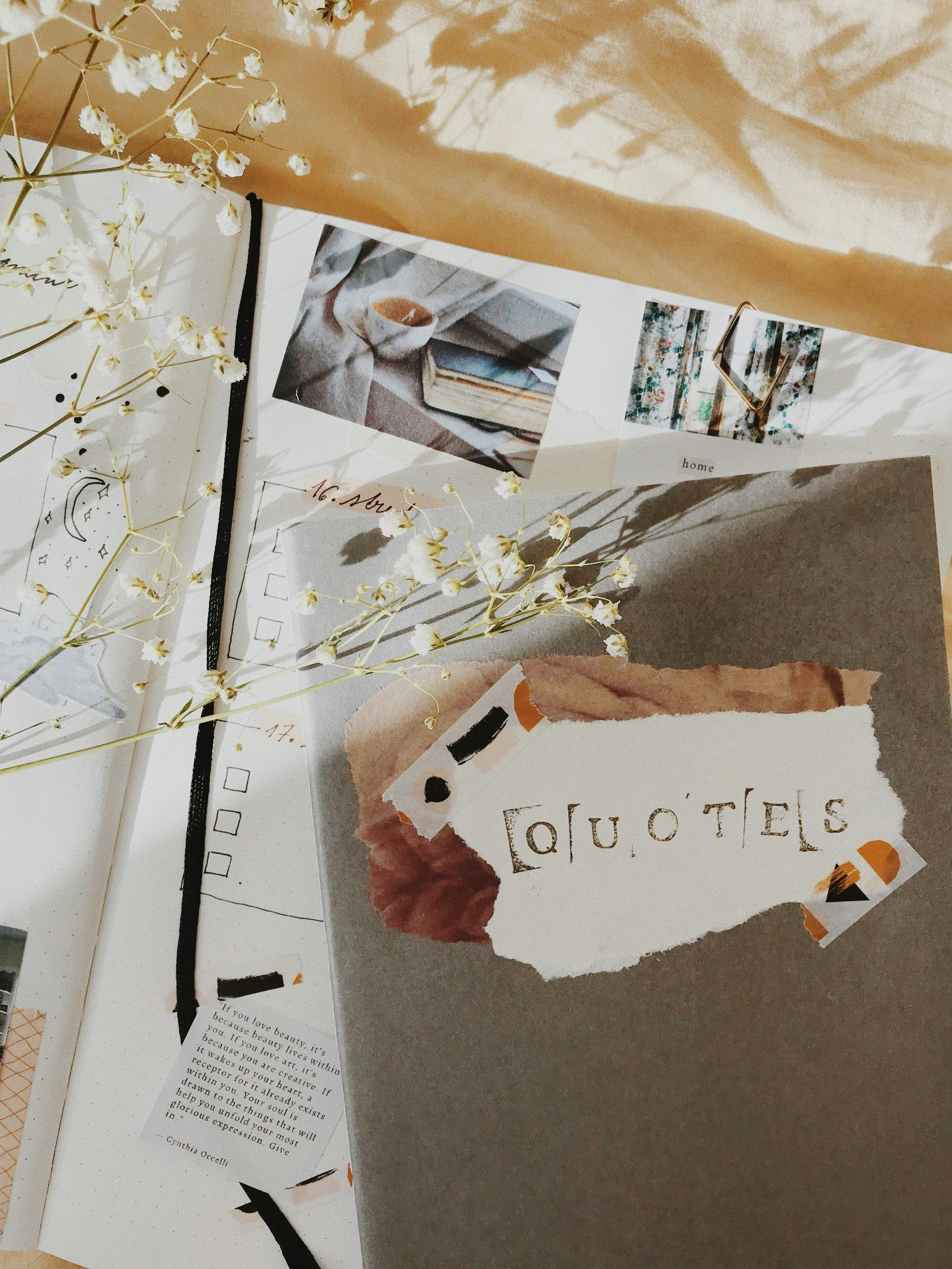 a closeup photo of a journal, scrap paper, and dried flowers