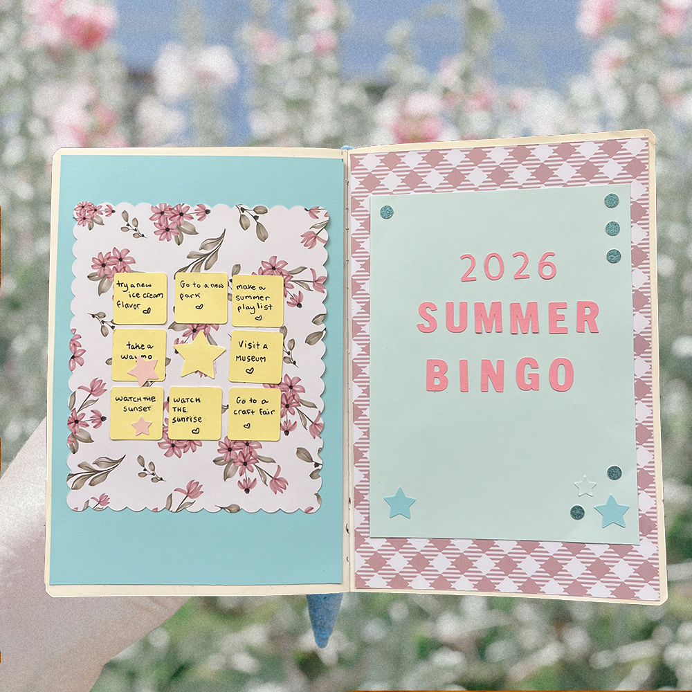 an open journal with a bingo card on the left side and text that reads " 2026 summer bingo" on the right side