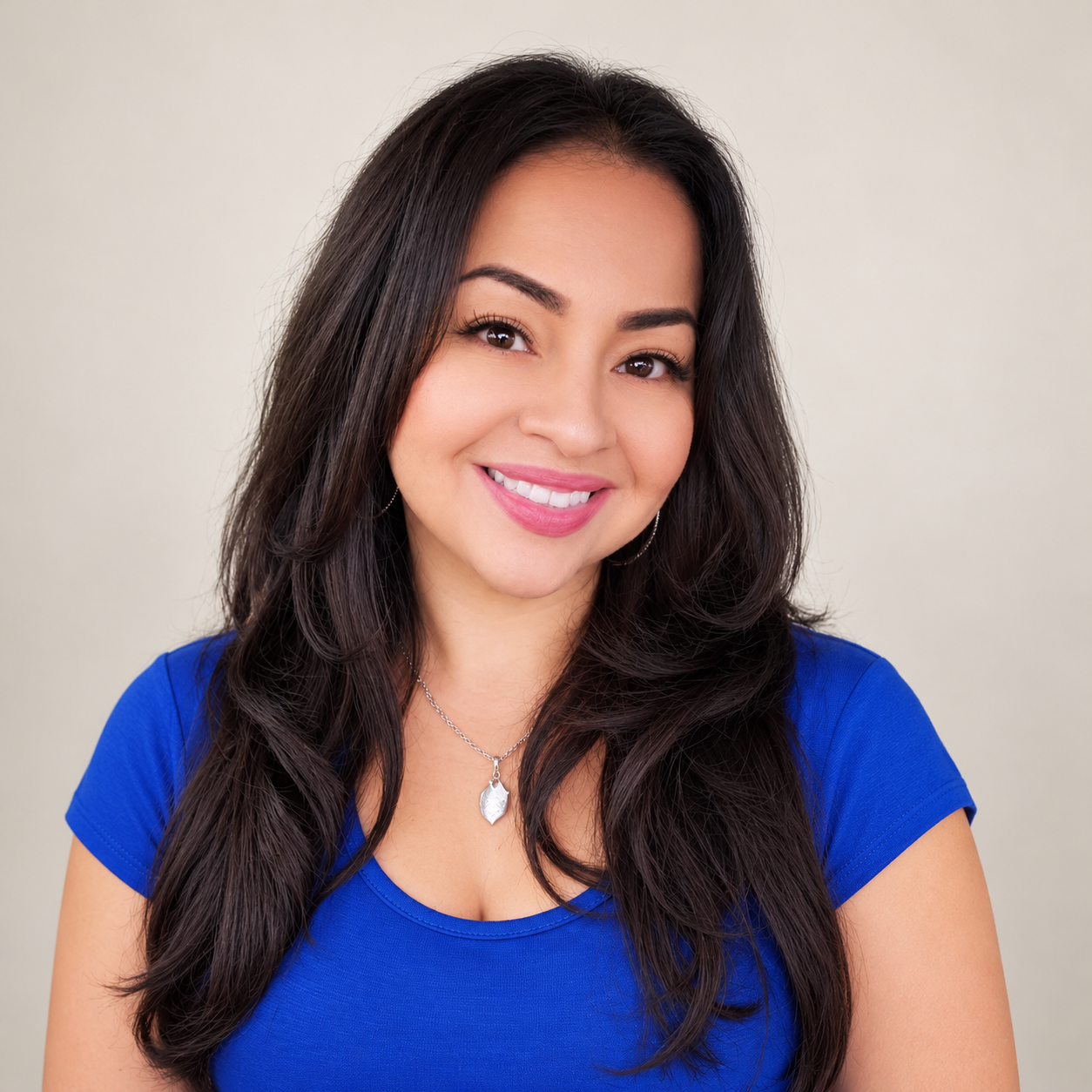 A woman with straight hair smiling in an indoor setting.