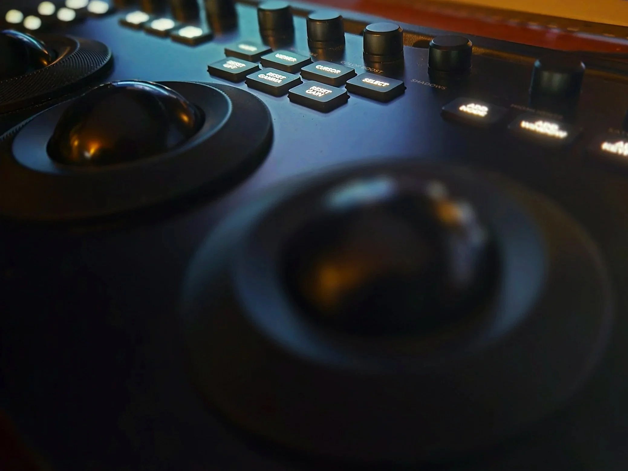 Close-up of colour grading console with buttons, knobs, and faders in a dimly lit environment.