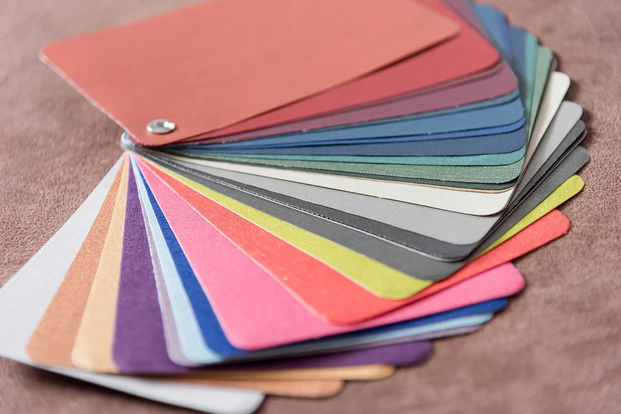 Fan of album cover material swatches in coral, navy, green, gray, pink, purple, and gold