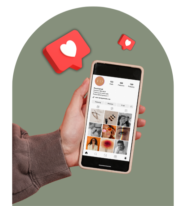 Person holding a smartphone displaying an Instagram profile, with two floating social media notification icons showing likes.