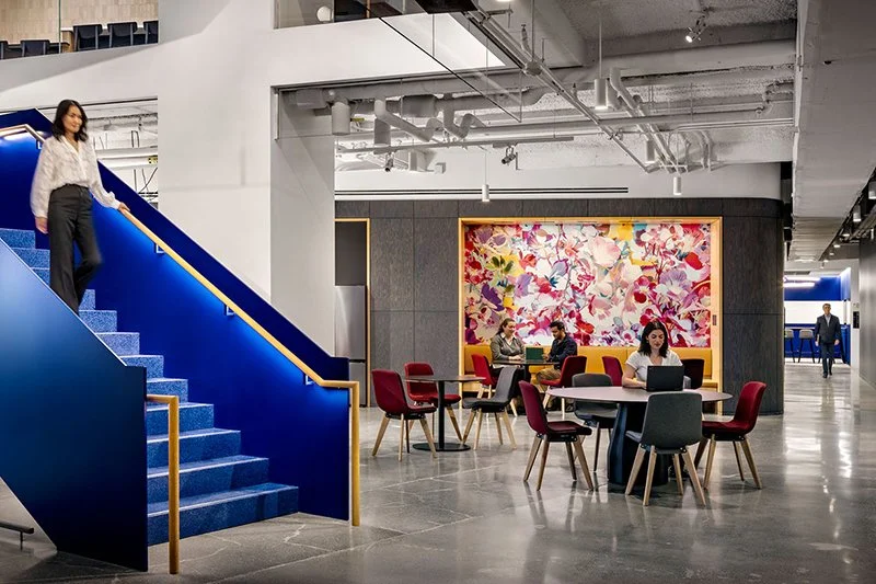 IBM office with blue stairway, open area with tables and chairs and large painting