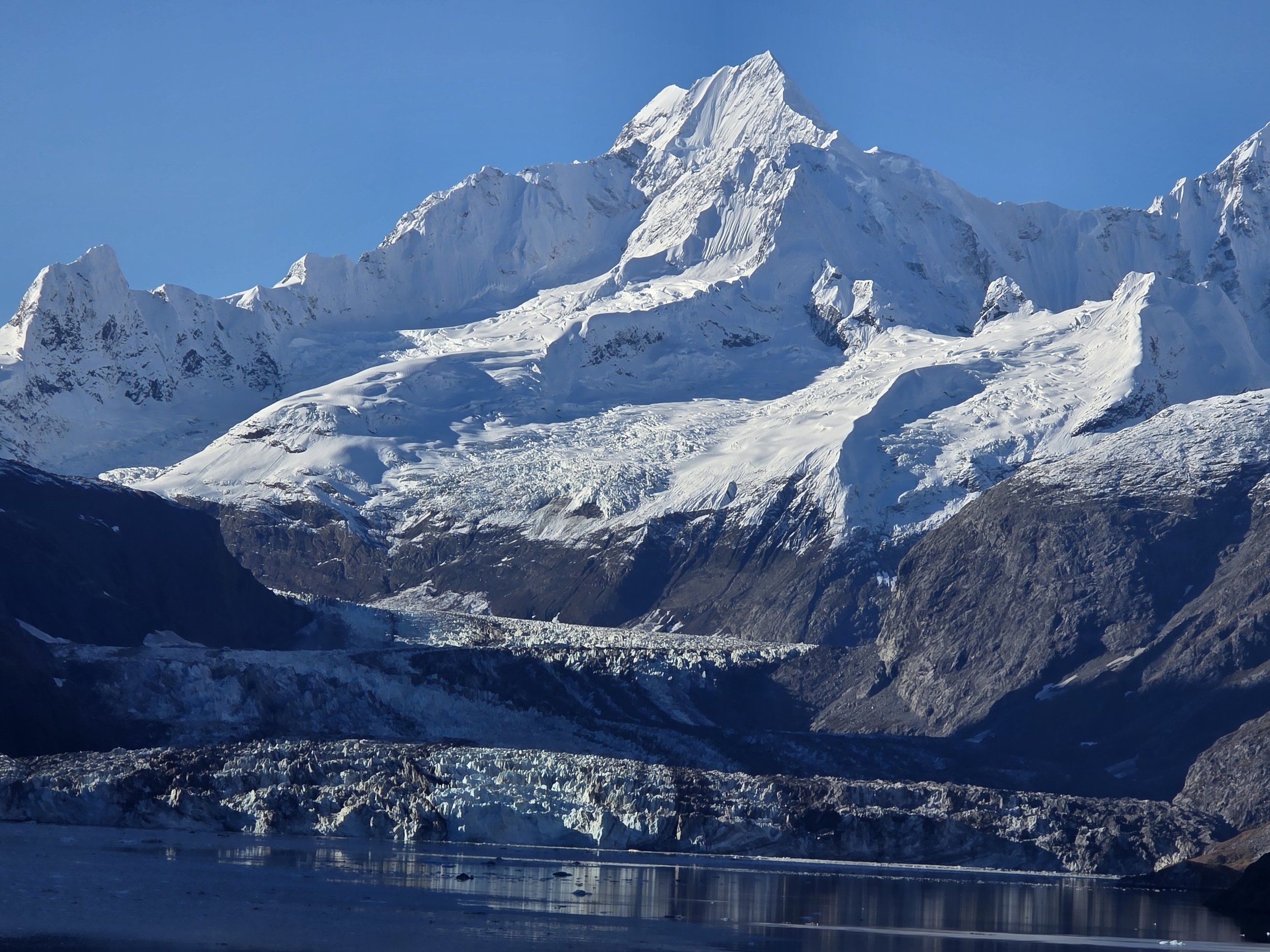 Snow-covered mountains rising above the waters of Glacier Bay, Alaska.