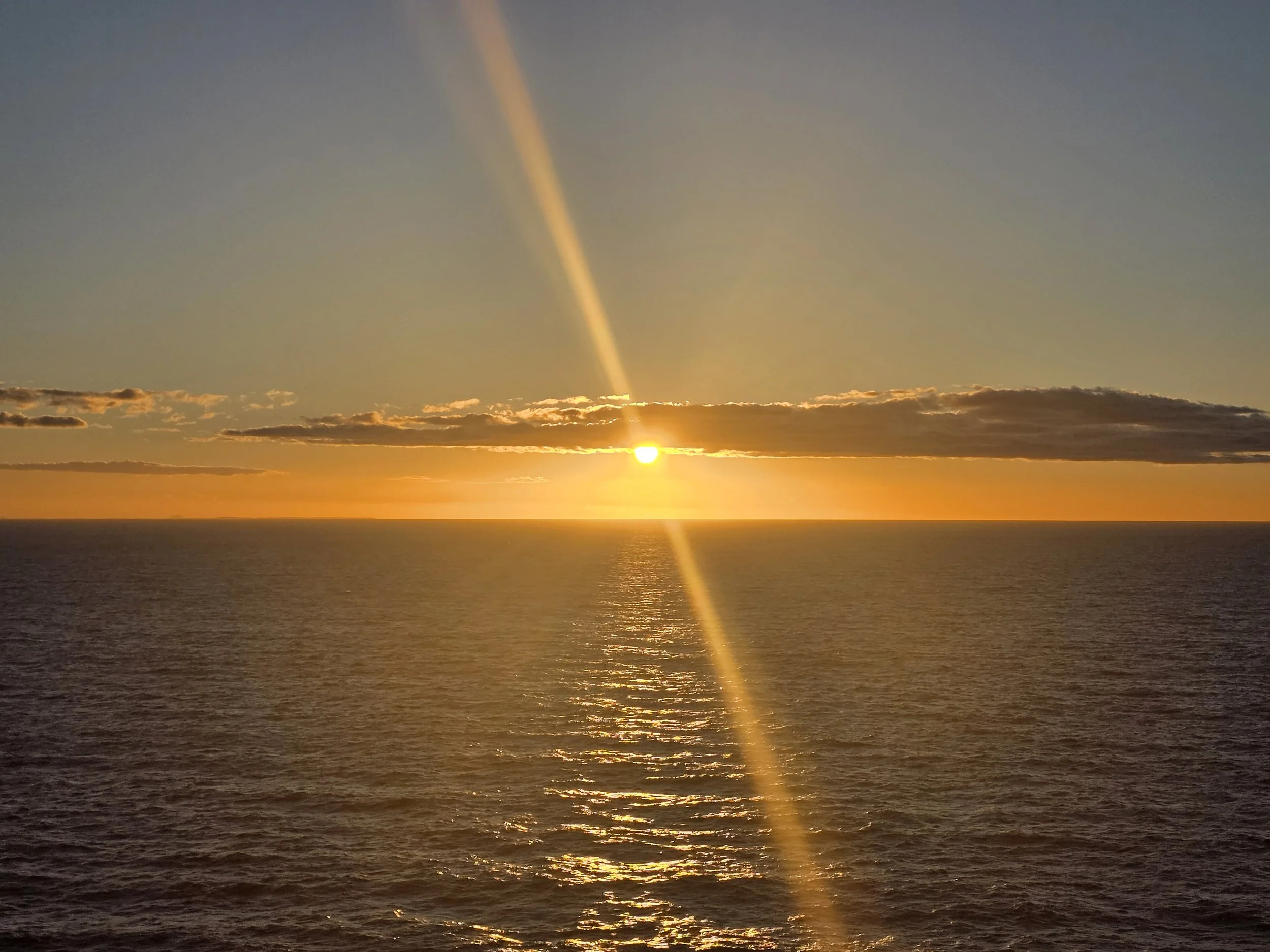 Golden sunset illuminating the clouds and ocean somewhere in the Pacific Ocean.