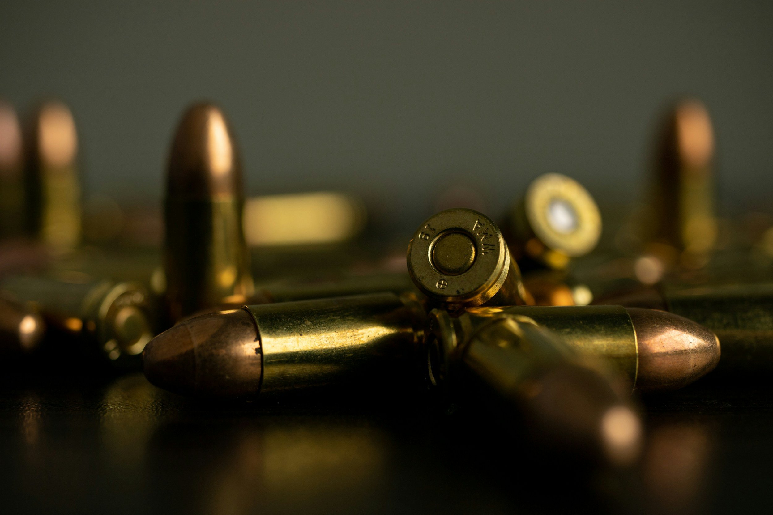 Several bullets and cartridges scattered on a dark surface, with a focus on a few bullets in the foreground. - AA Wholesale | Amory | MS | Wholesale | Deals | Amory Auction