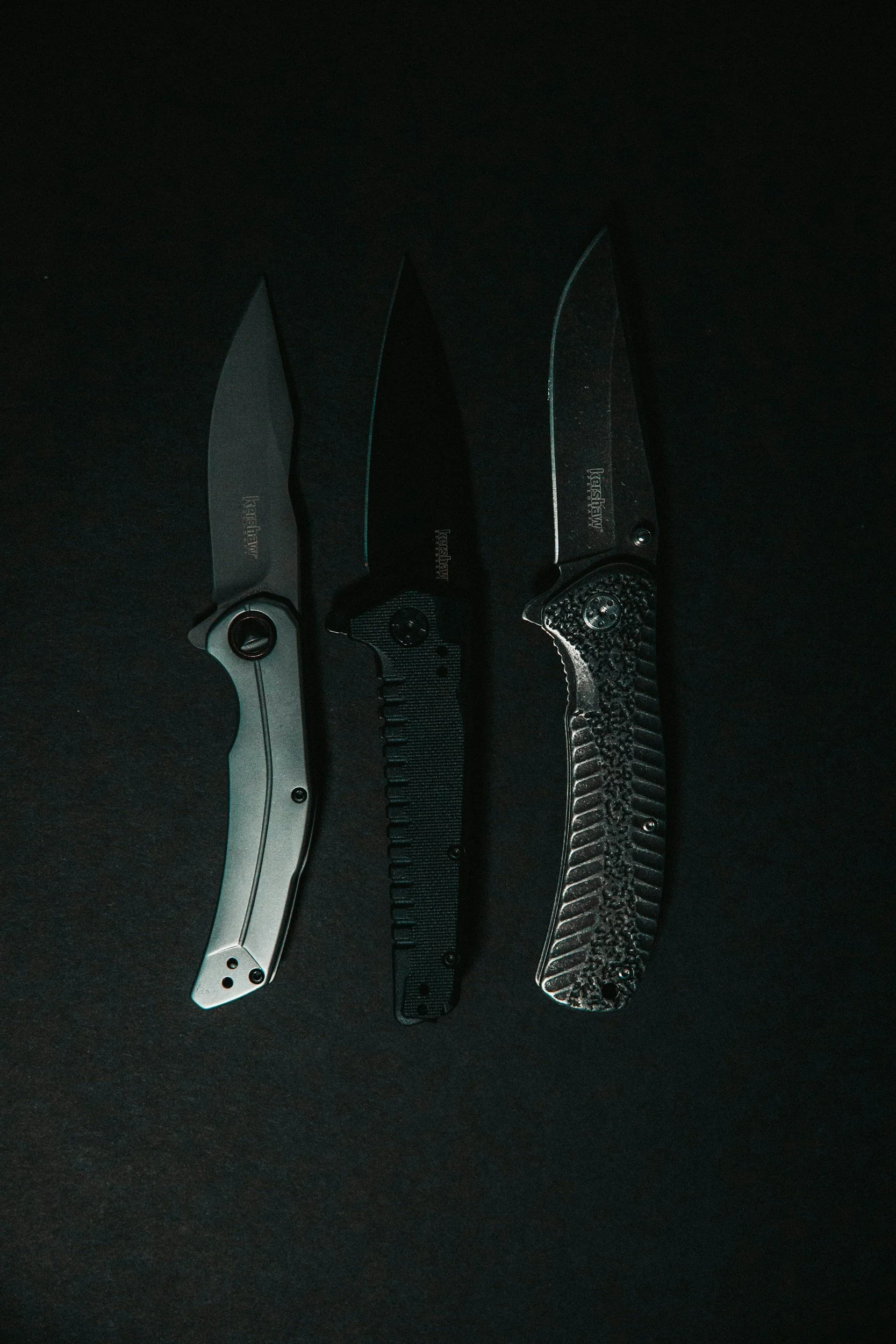 Three knives with different handles and blades, displayed against a black background. - AA Wholesale | Amory | MS | Wholesale | Deals | Amory Auction