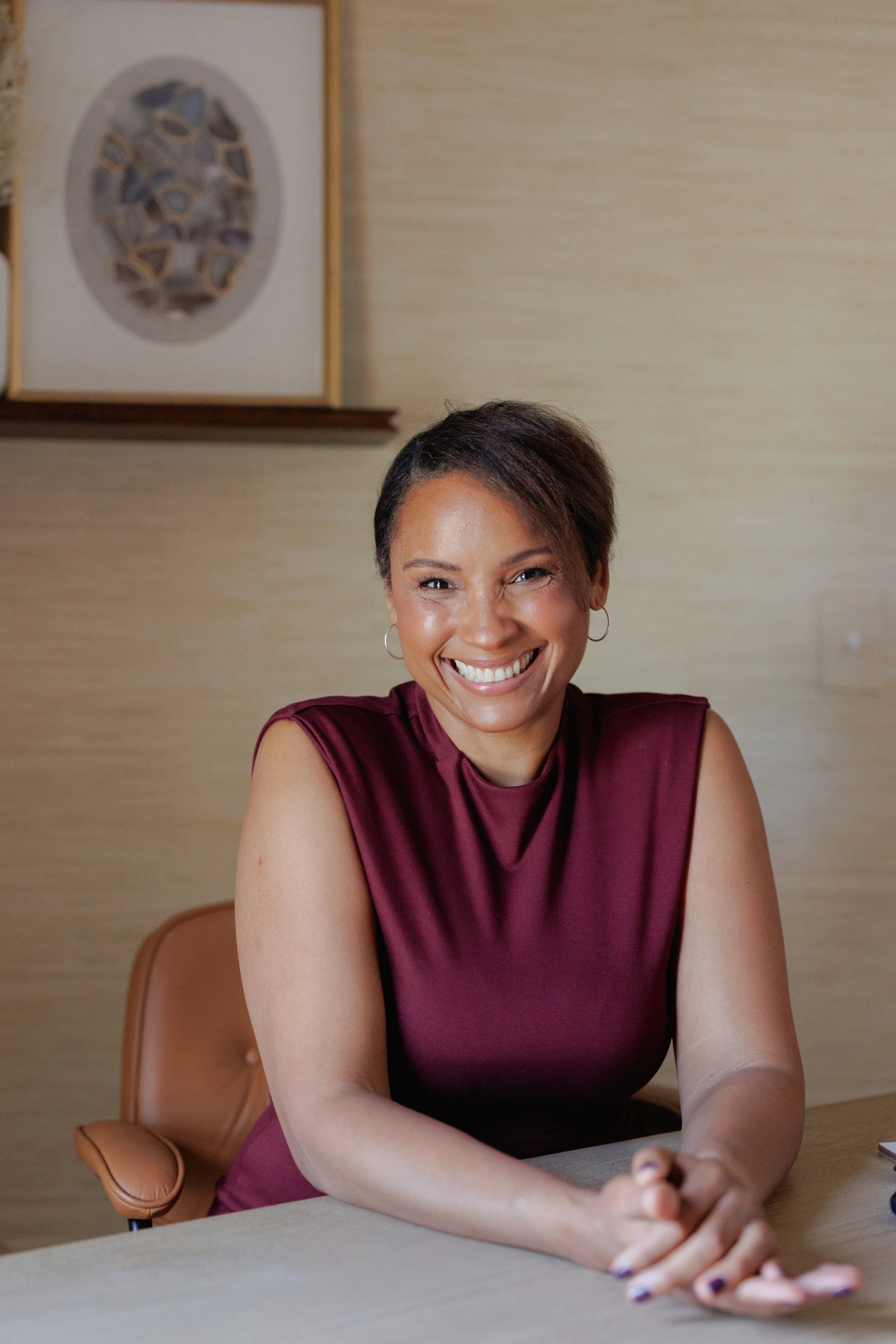 Smiling woman with short hair sitting at a table in an office setting.