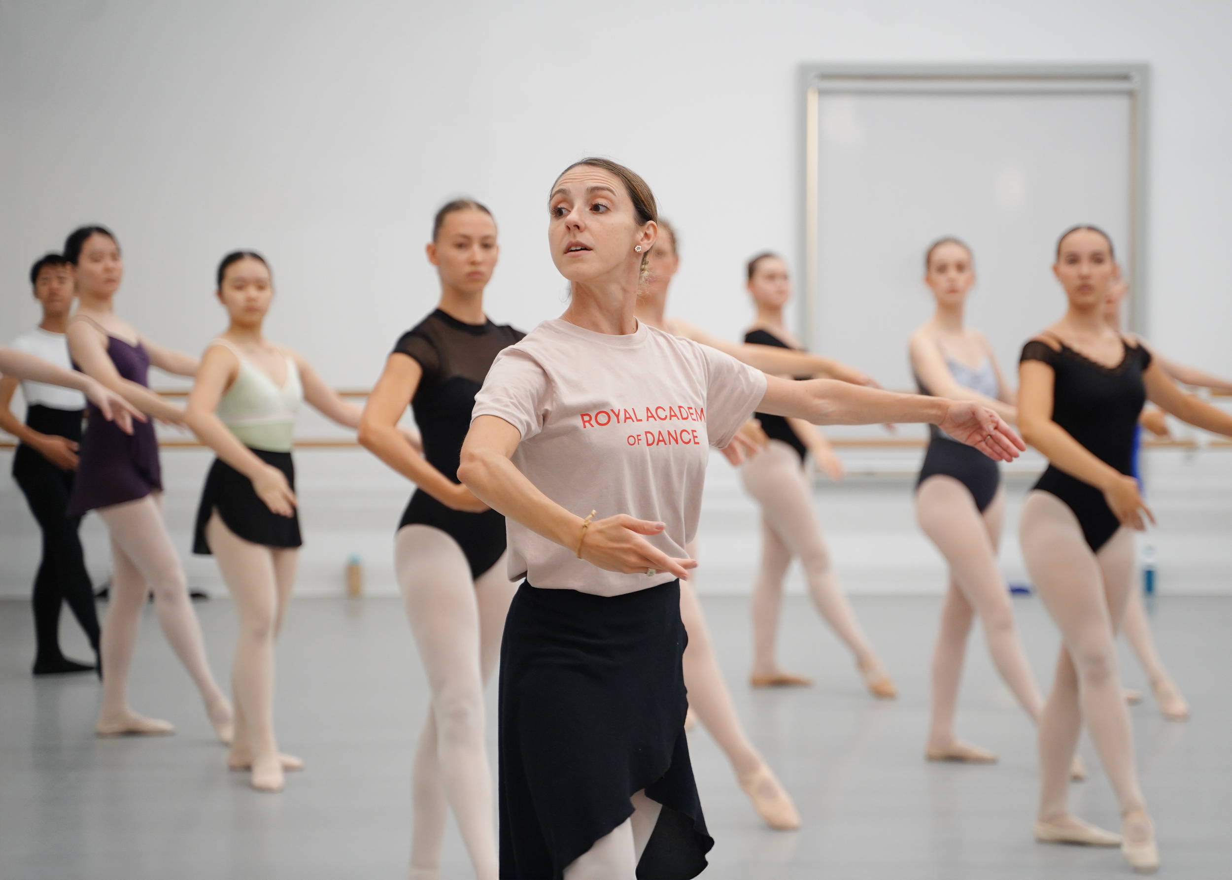 Ballet class with a dance instructor and students practicing in a dance studio.