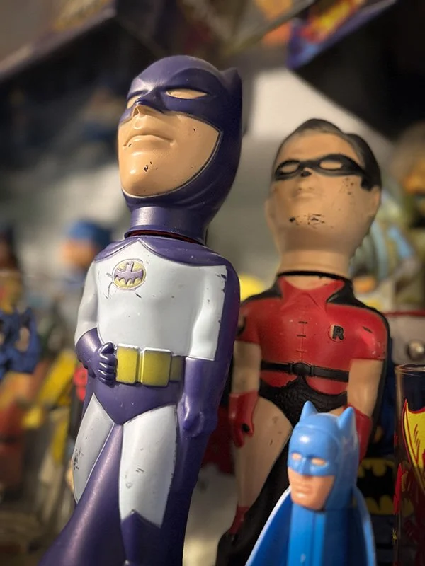 Vintage Batman and Robin action figures displayed among a collection of classic superhero toys, representing the nostalgia and storytelling behind pop culture collecting.