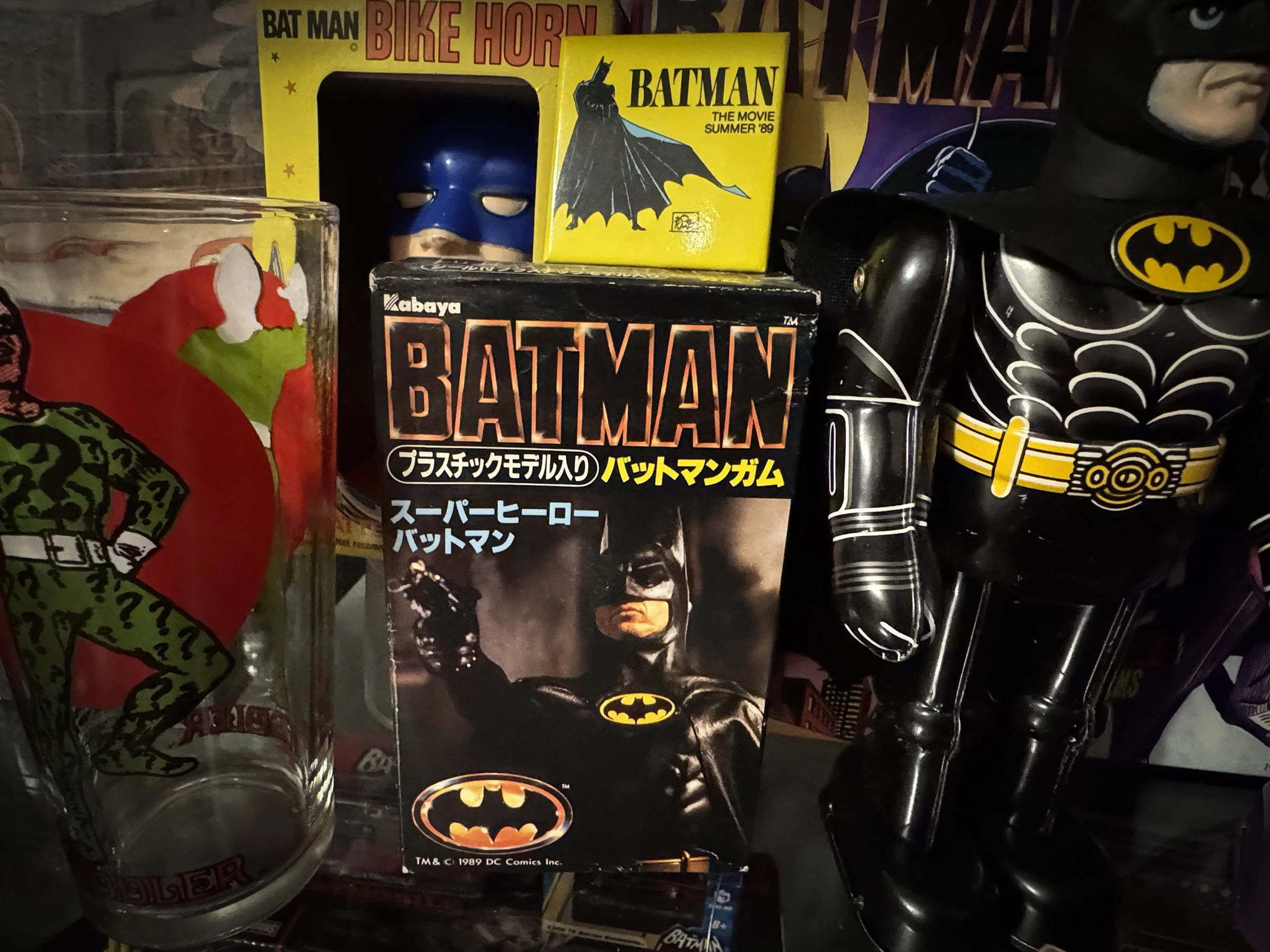 A display of Batman '89 movie memorabilia including a Kabaya Batman plastic model kit from Japan and other movie merchandise.