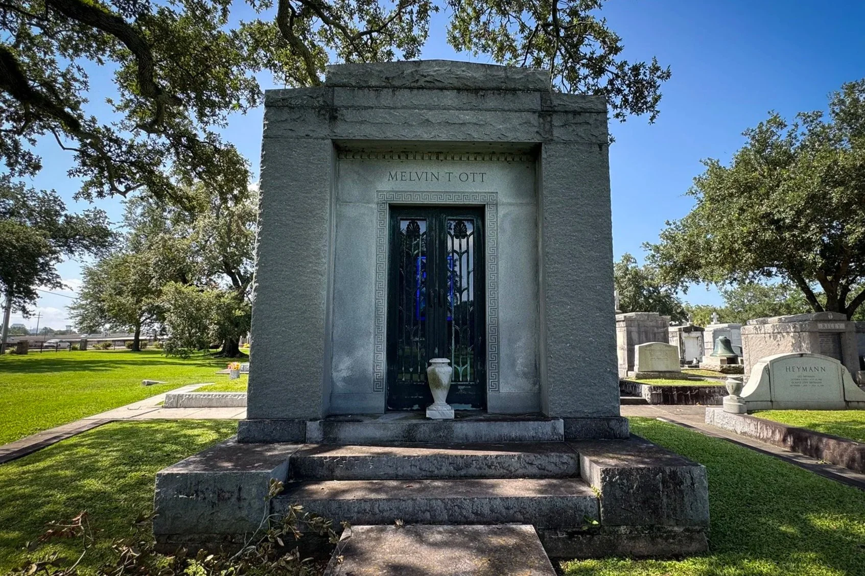 Melvin T. Ott family mausoleum beneath live oak trees in Metairie Cemetery.