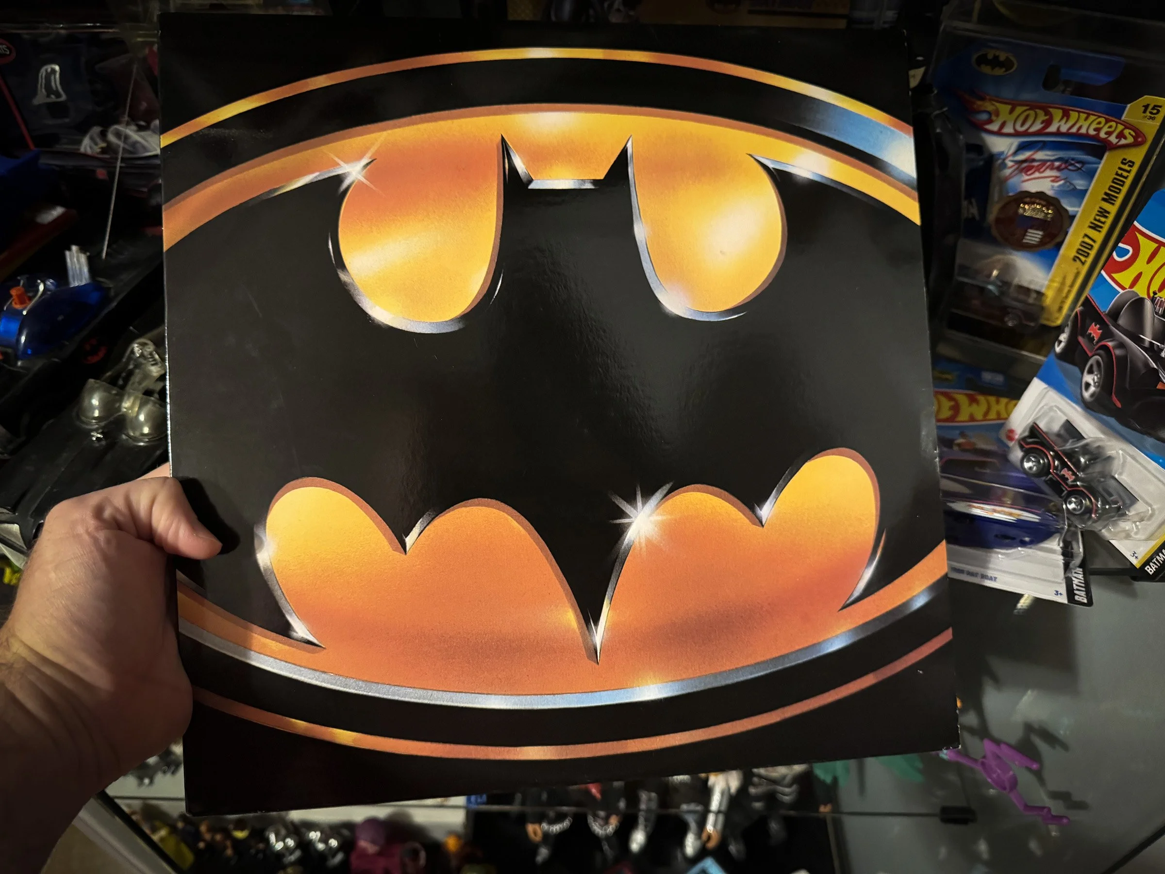 The Batman (1989) soundtrack album displaying the iconic yellow-and-black bat logo, photographed in front of a Batman-themed collection.