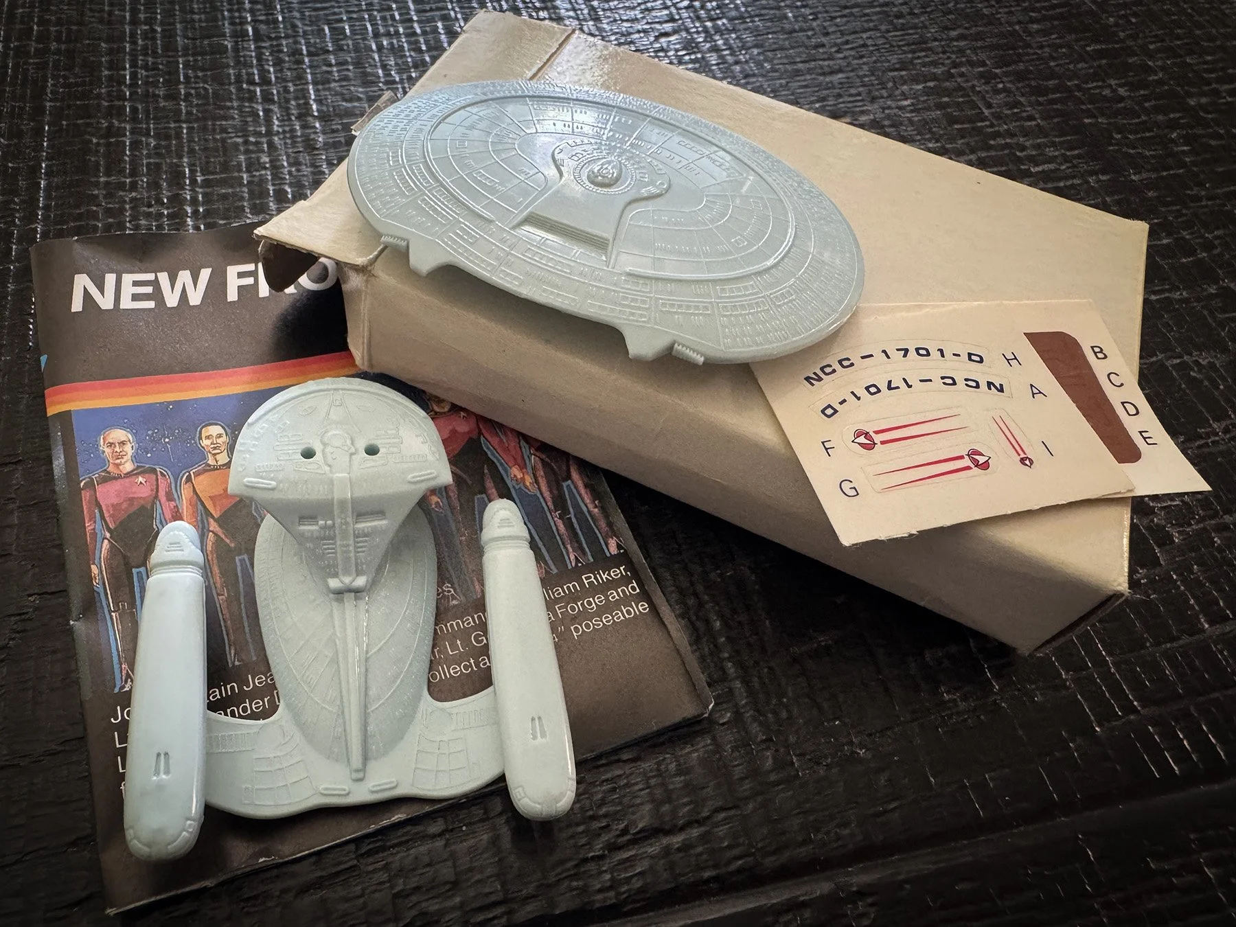 1987 General Mills Star Trek: The Next Generation giveaway Enterprise-D with original box, decal sheet, instructions and molded plastic parts displayed on a tabletop.