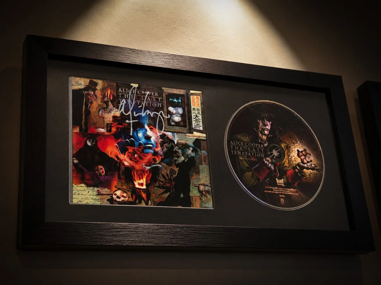 Signed copy of Alice Cooper’s The Last Temptation CD displayed with the disc in a black frame beneath a gallery-style spotlight.