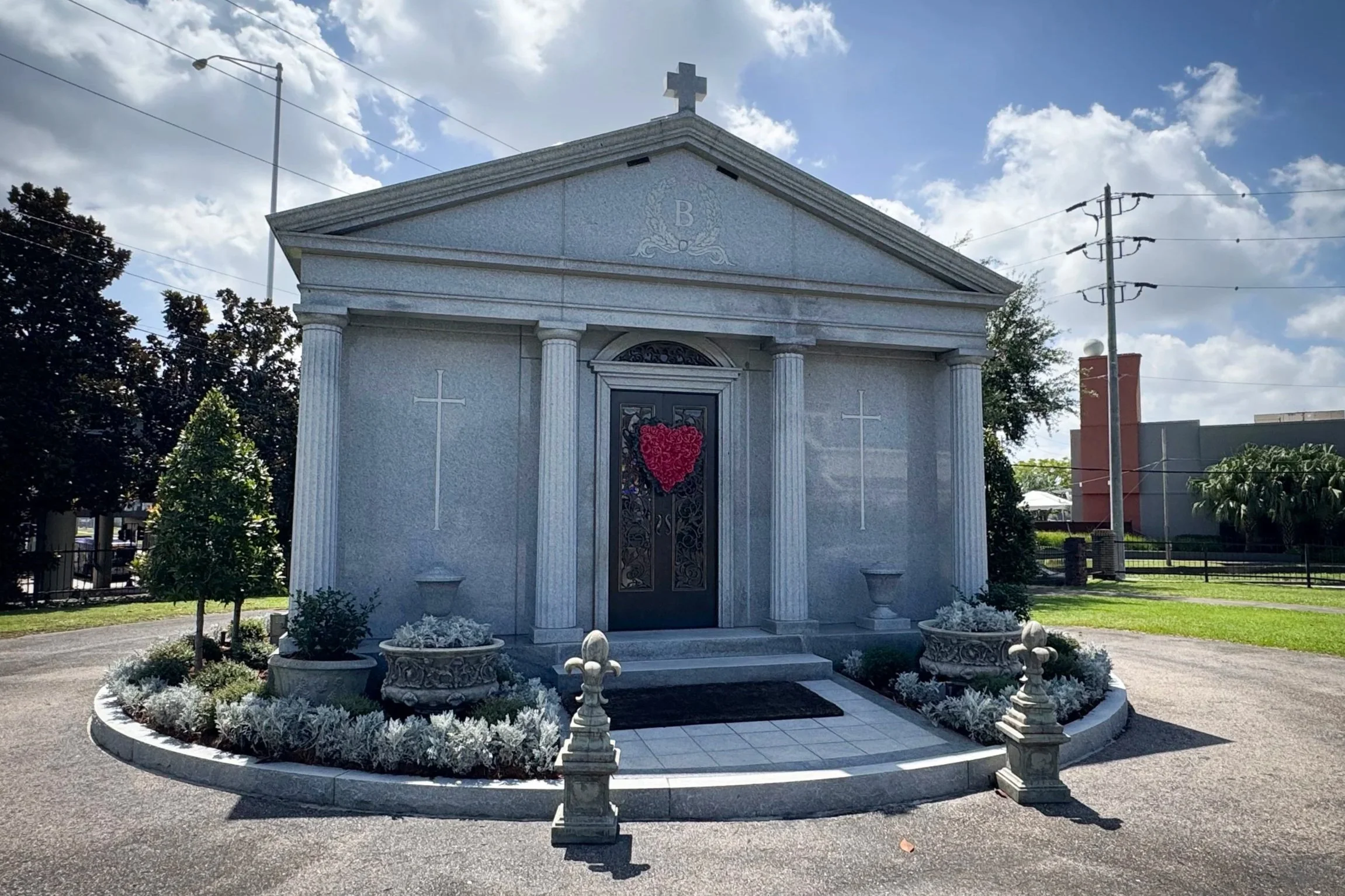 Tom Benson family mausoleum with four columns, a broad pediment and bronze doors in Metairie Cemetery.
