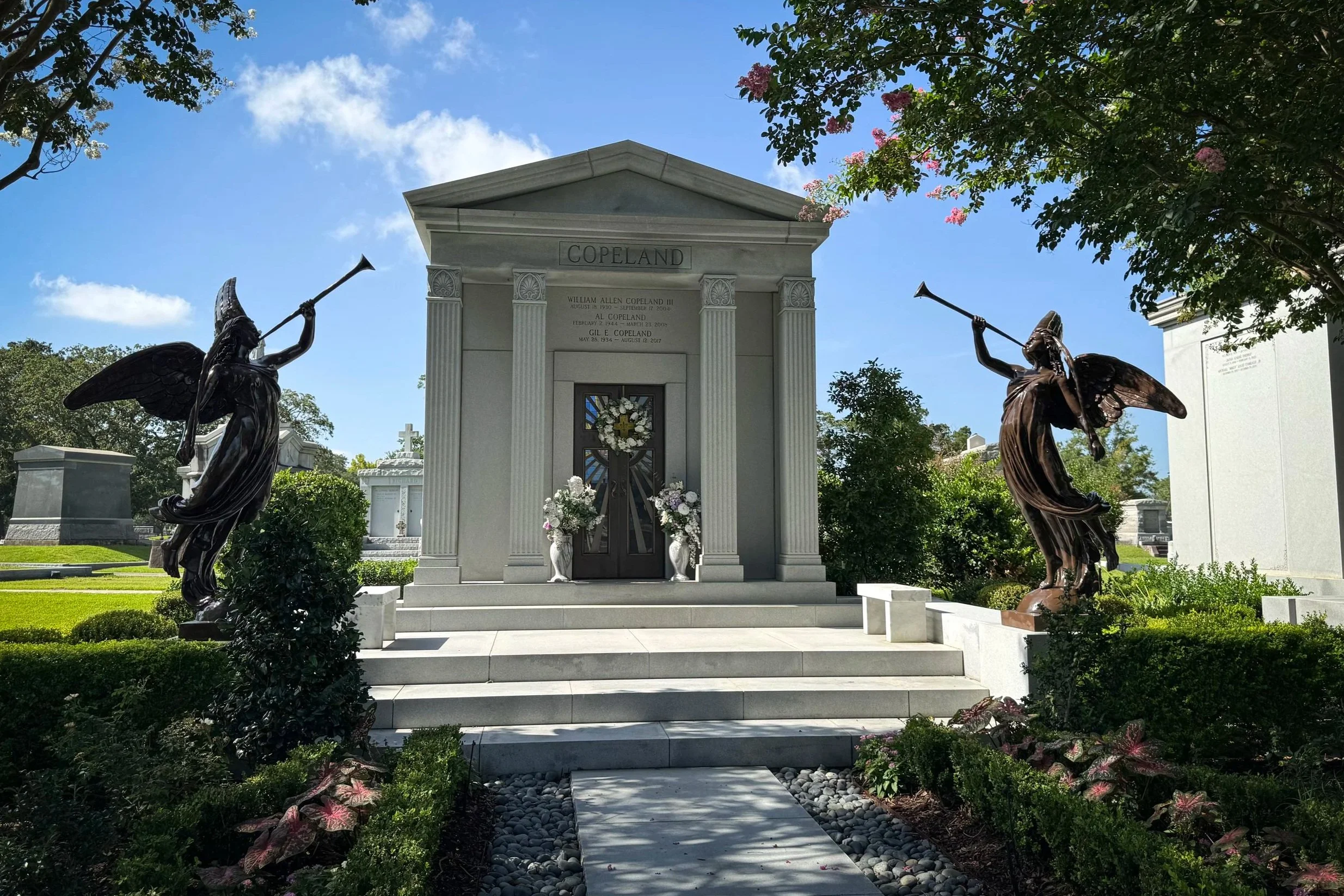 Al Copeland family mausoleum flanked by two bronze angels in Metairie Cemetery.