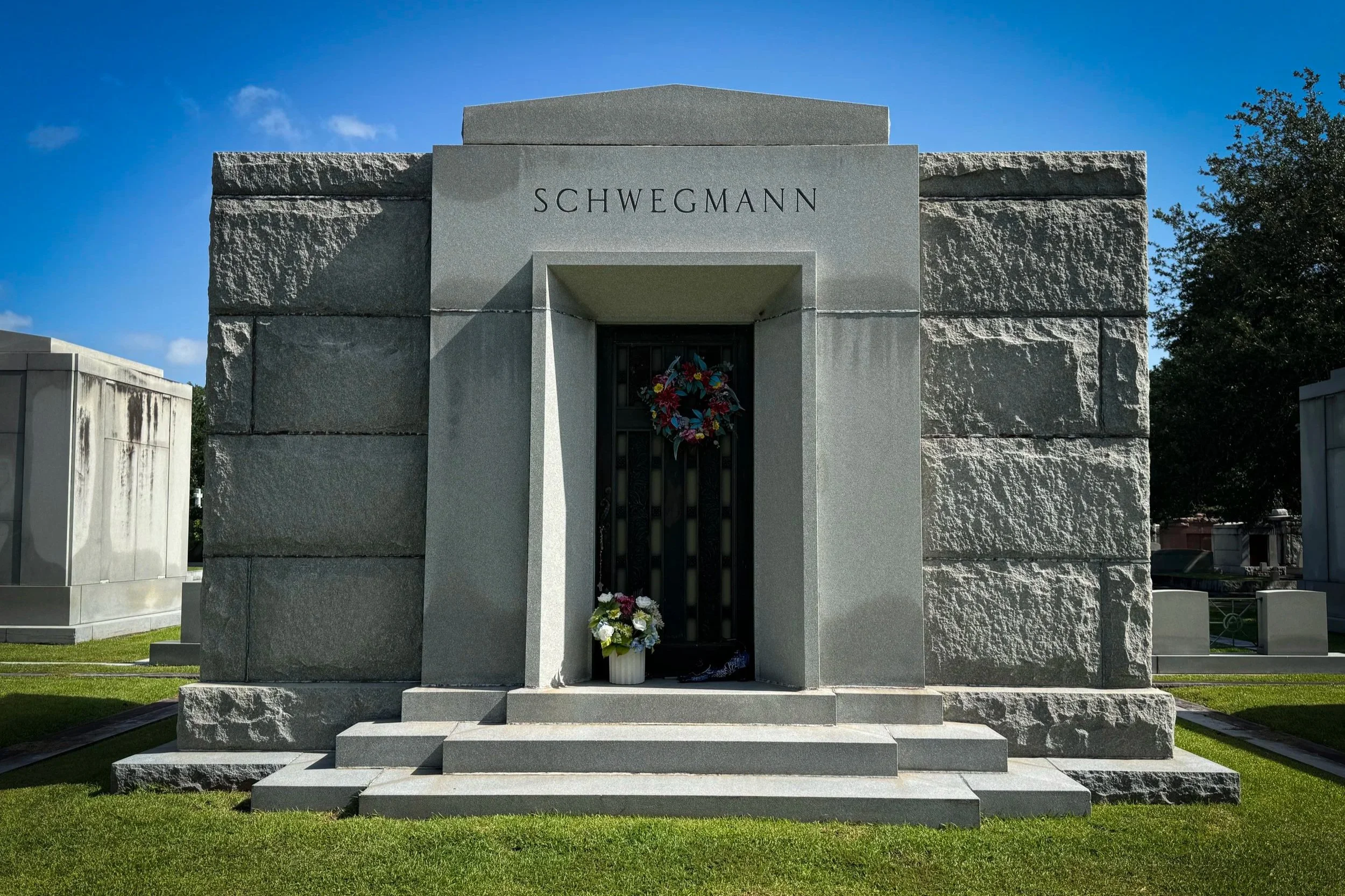 Schwegmann family mausoleum with rough-cut granite walls in Metairie Cemetery.