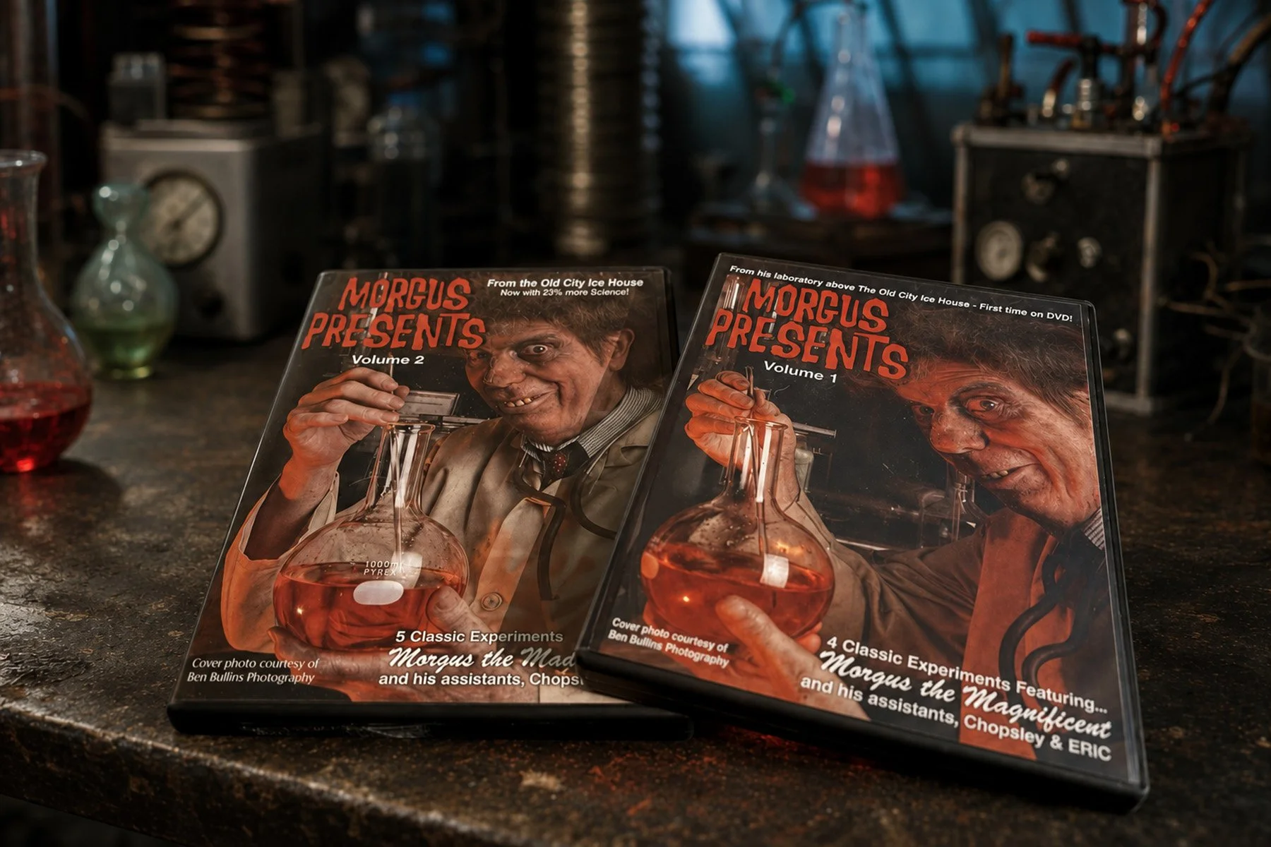 Morgus Presents Volumes 1 and 2 DVD cases displayed on a laboratory workbench surrounded by vintage scientific equipment.