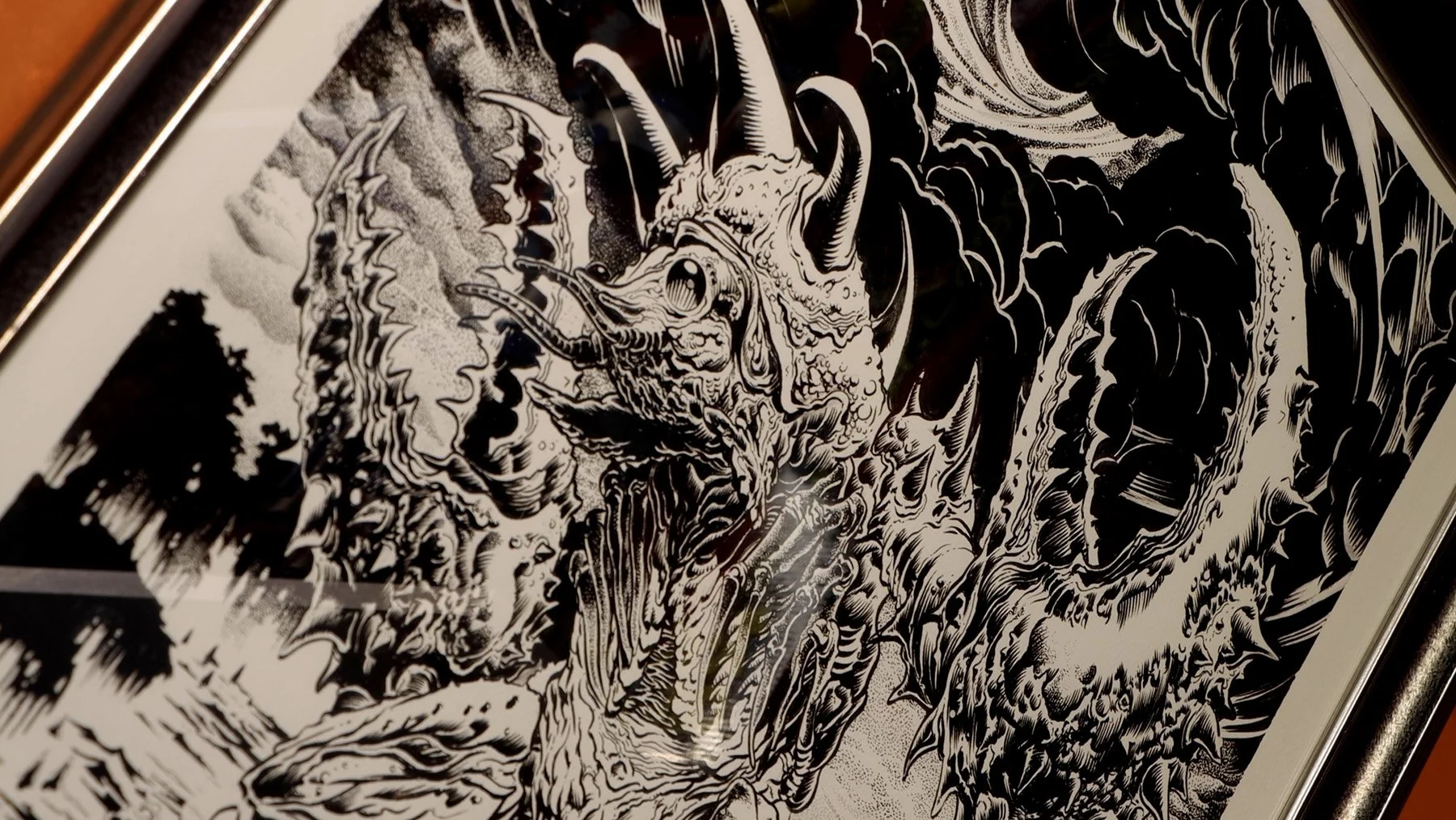 Framed black-and-white illustration showing a heavily detailed horned kaiju surrounded by other monstrous creatures.