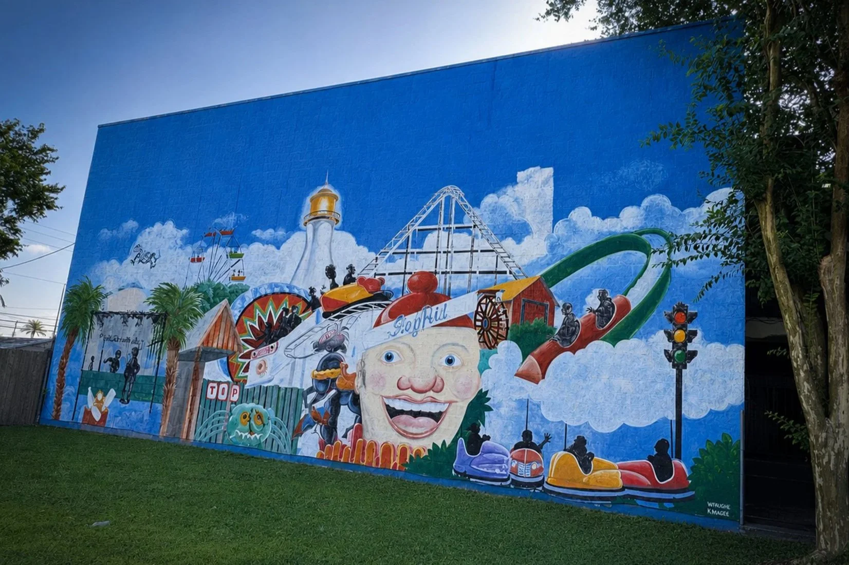 Colorful Rivertown mural depicting Pontchartrain Beach attractions, including the Zephyr roller coaster, lighthouse, Sky Ride, giant clown and other iconic New Orleans amusement park landmarks.