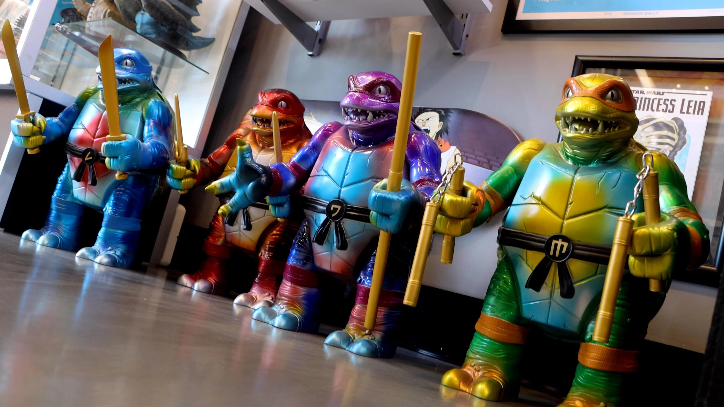 Large colorful ninja turtles figures displayed in a row inside Hidden Dimension Studio.