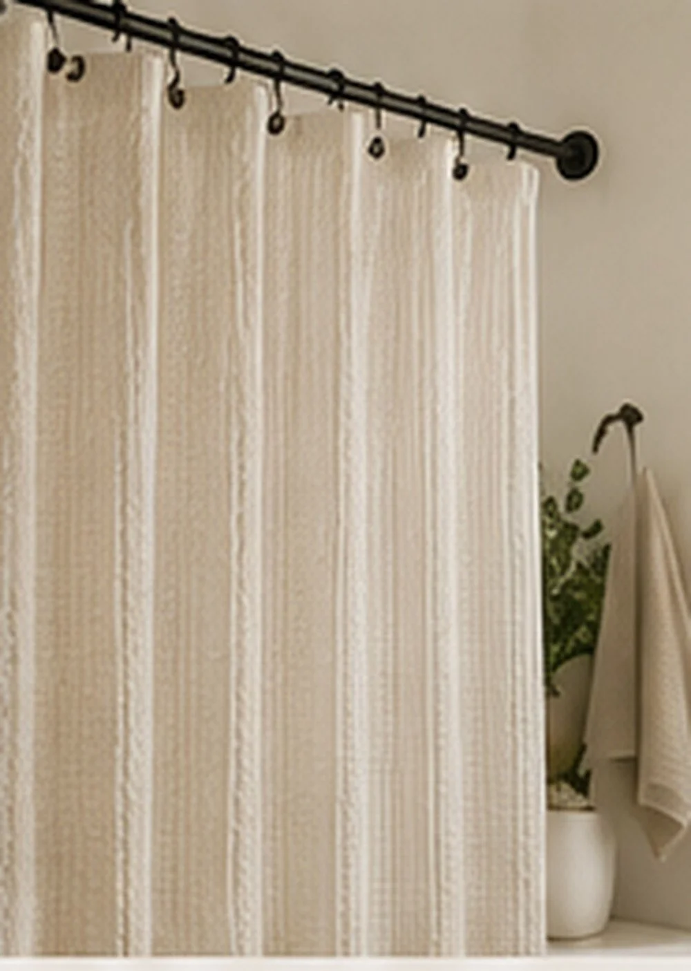Neutral bathroom shower curtain on a black curtain rod with soft fabric texture.