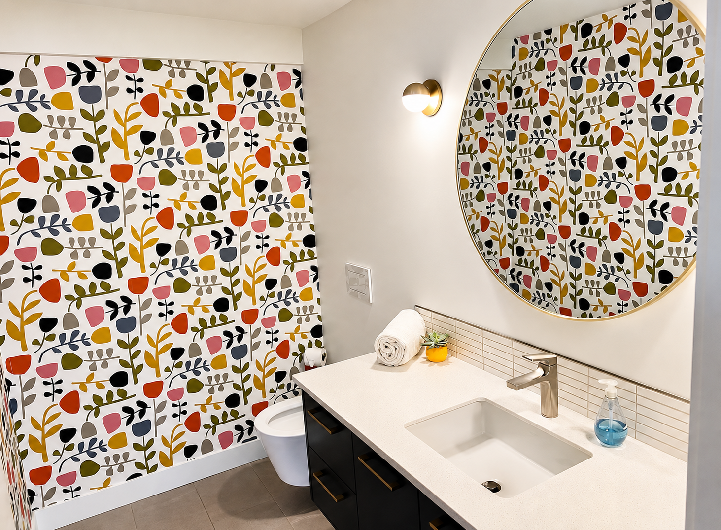 Modern bathroom with a colorful floral-patterned shower curtain, round mirror, white countertop, black cabinetry, and a small potted plant.