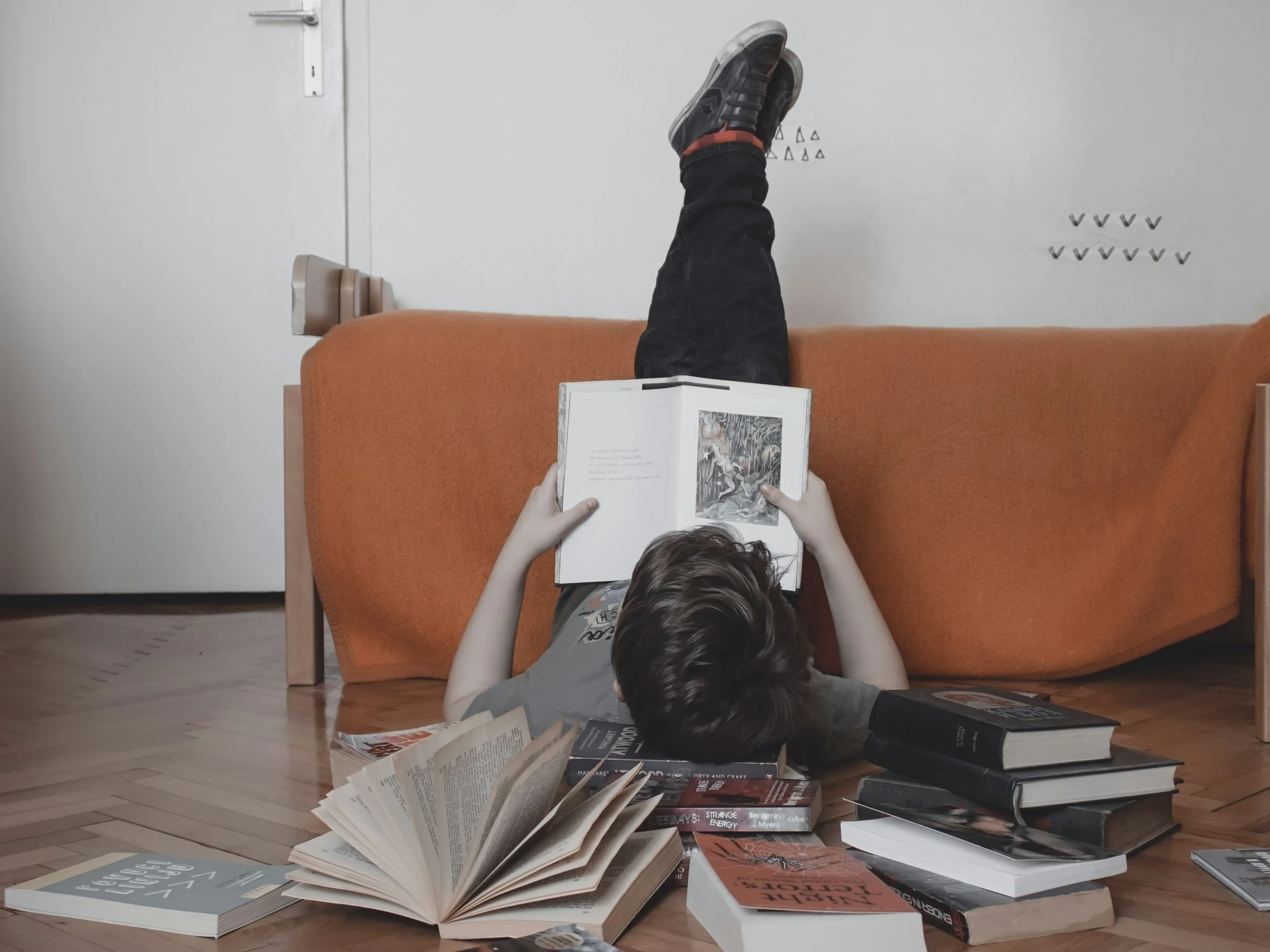Graphic for literacy therapy. Child reading a book. Nearby, are piles of books.