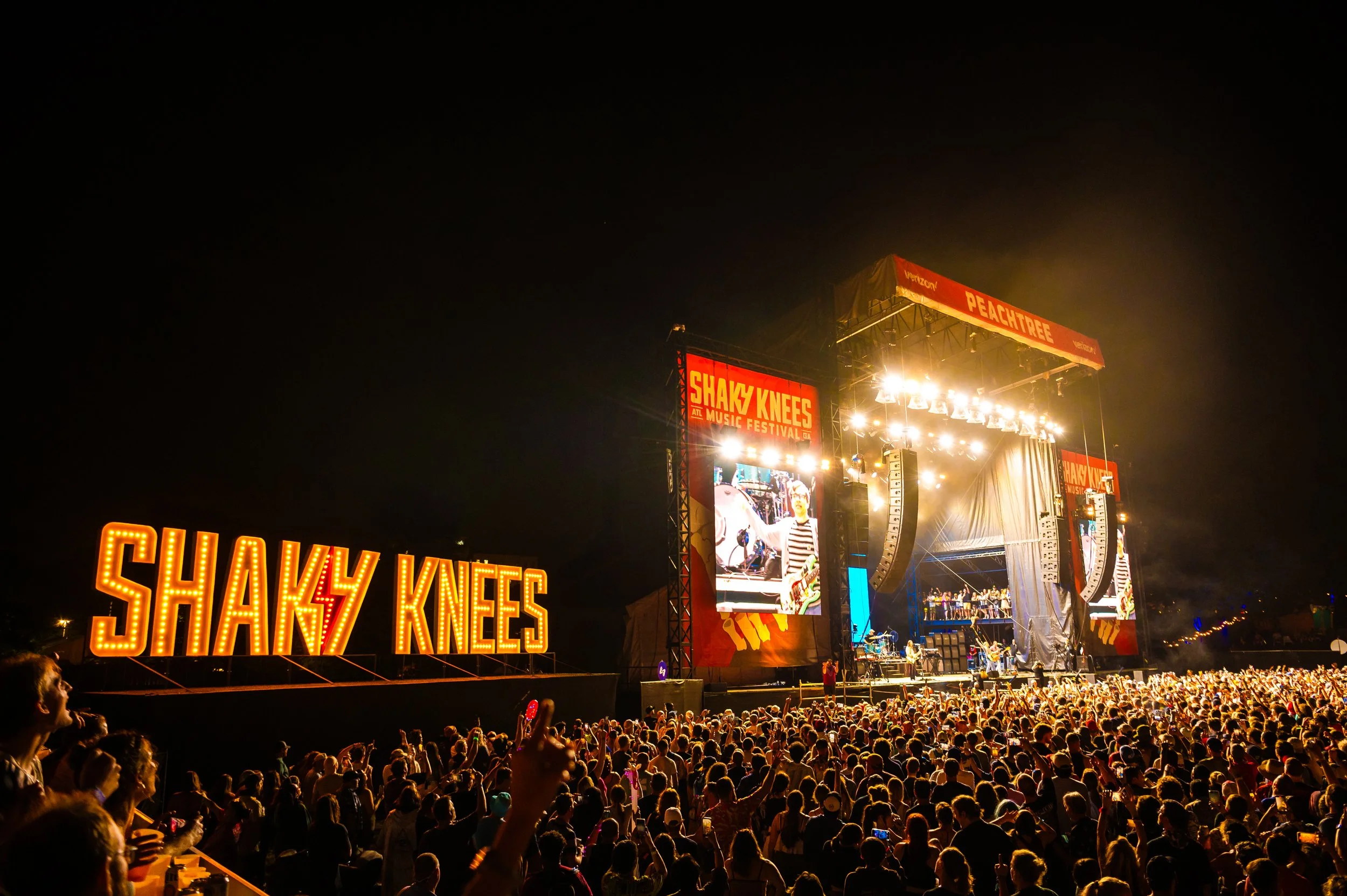 Illuminated Shaky Knees Music Festival sign with crowd at Atlanta concert