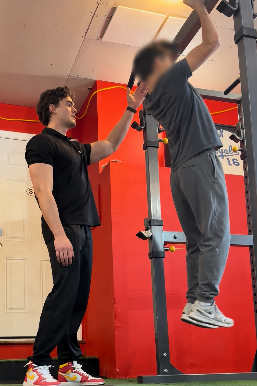 Billy Vetter coaches a client during a pull-up exercise in a private gym.